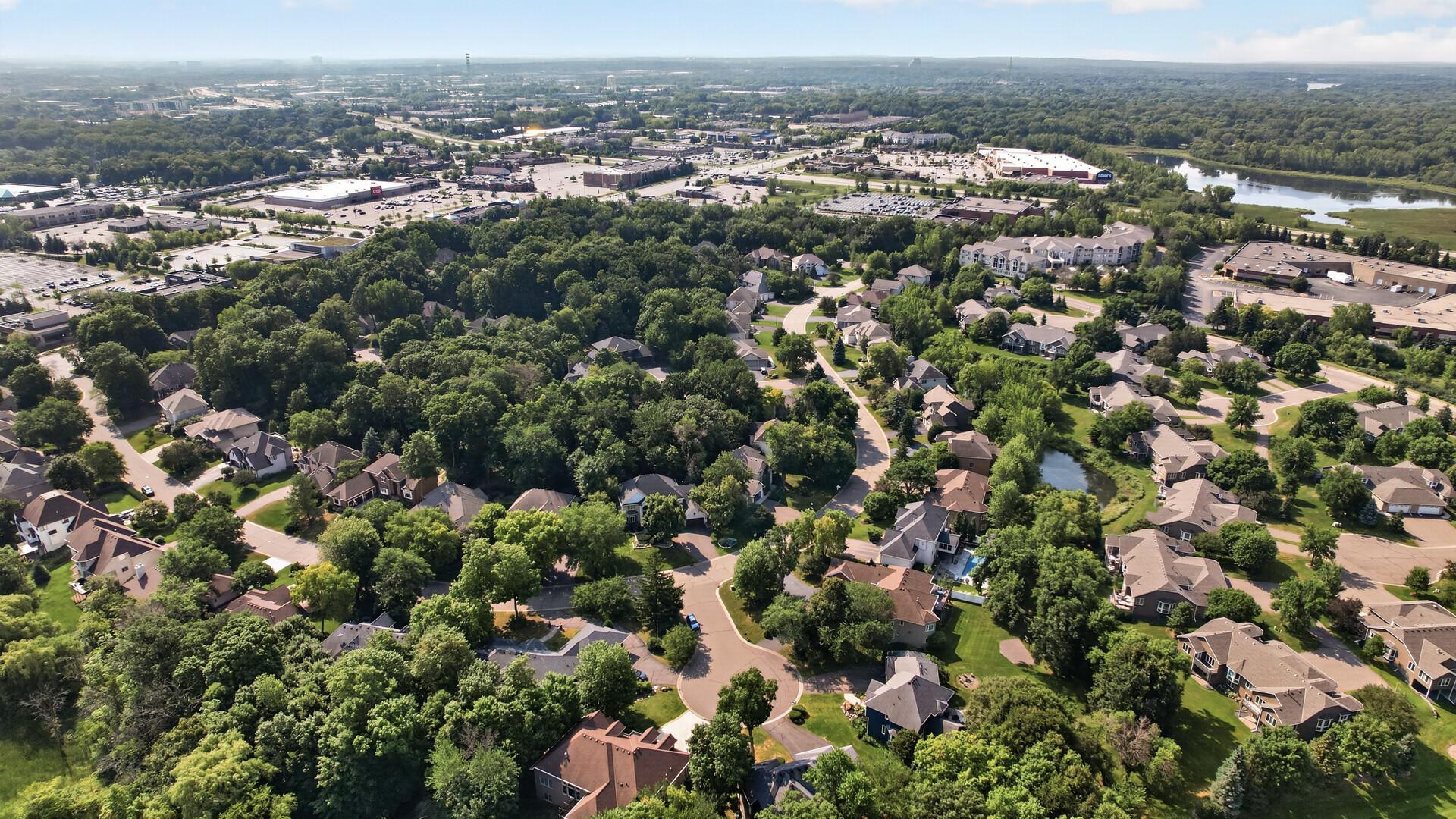 Aerial view of a leafy Plymouth neighborhood with winding streets, homes, and a pond.