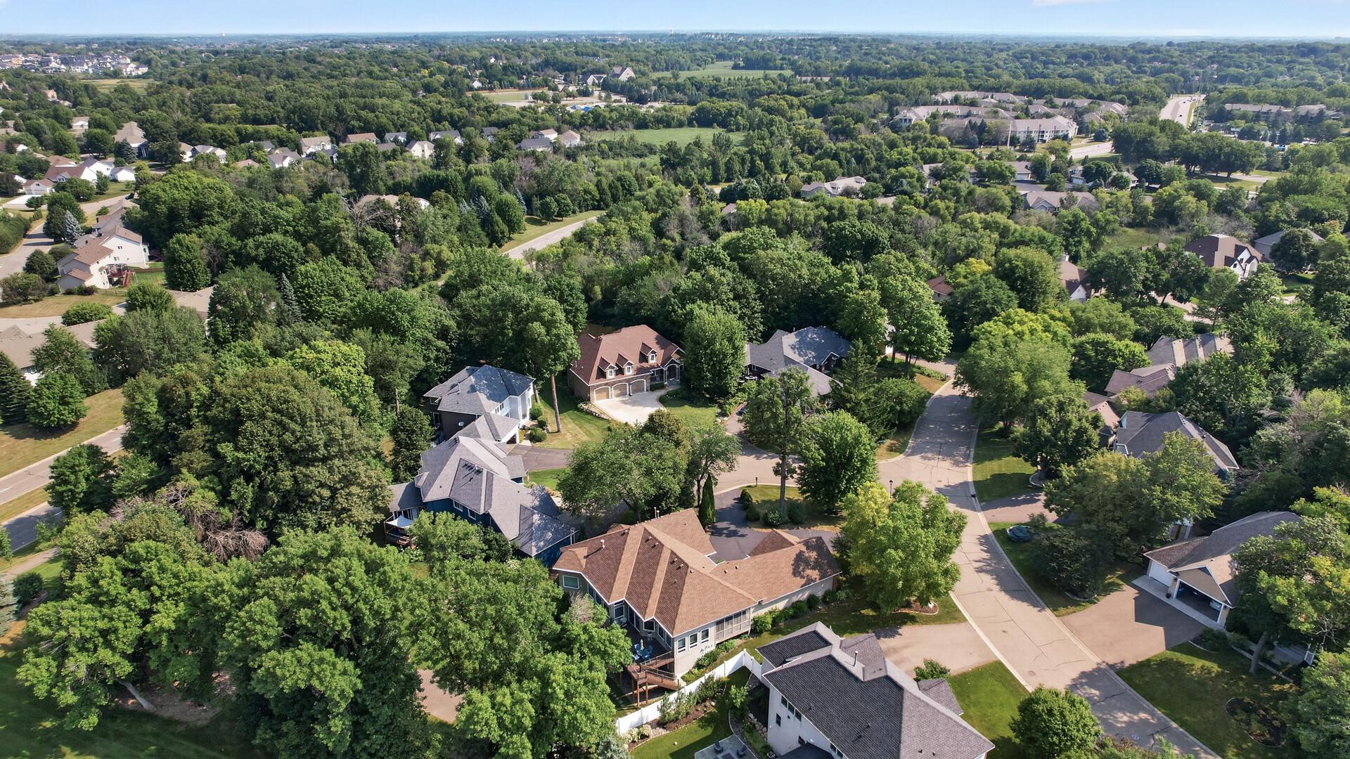 Aerial view of a tree-lined neighborhood with detached homes and winding streets.