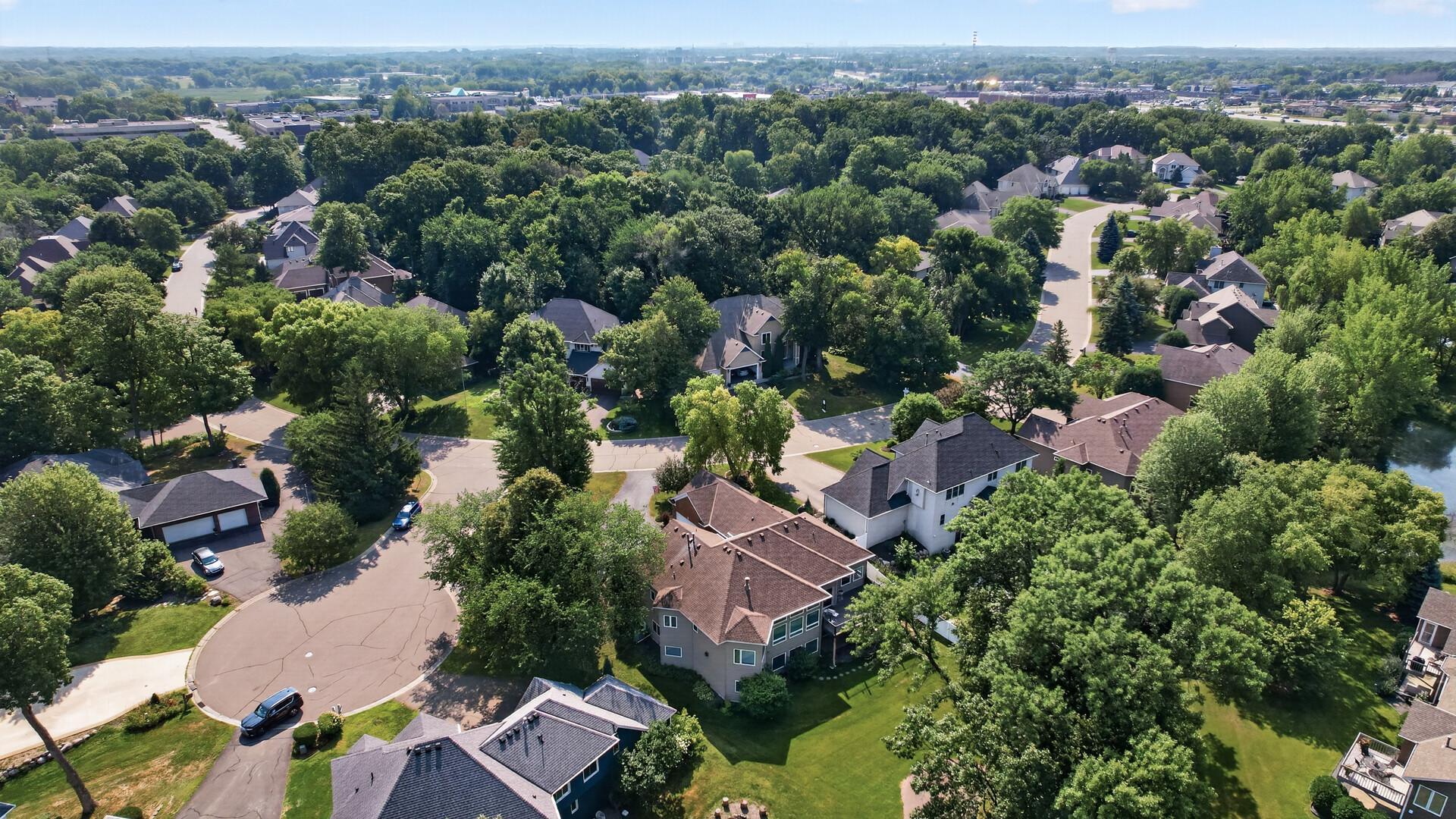 Aerial view of a leafy residential neighborhood with detached homes and a curved cul-de-sac.