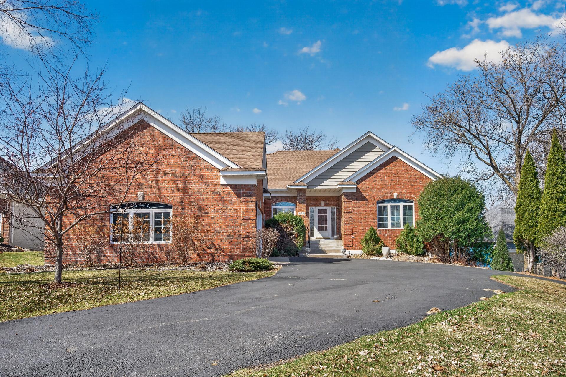 Red-brick home with multiple gables and a curved driveway, framed by leafless trees.