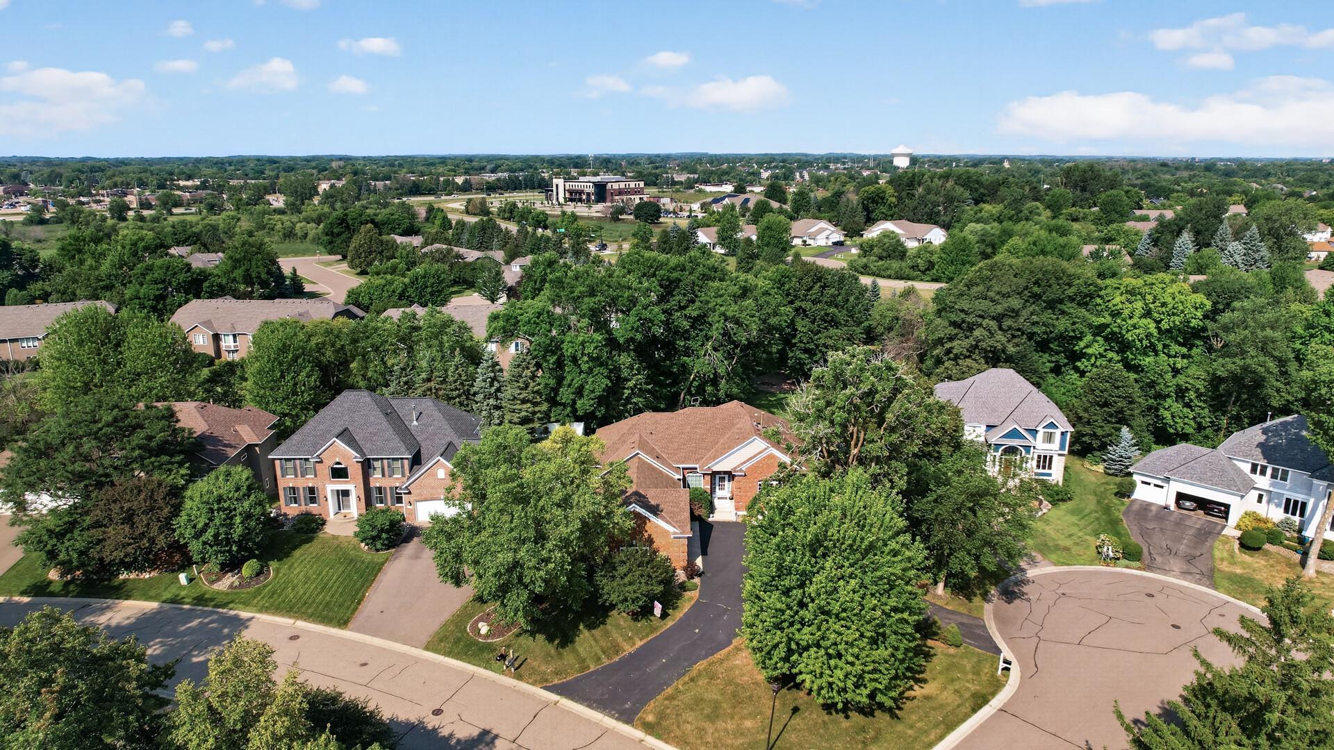 Aerial view of a leafy residential neighborhood with detached homes and a cul-de-sac.