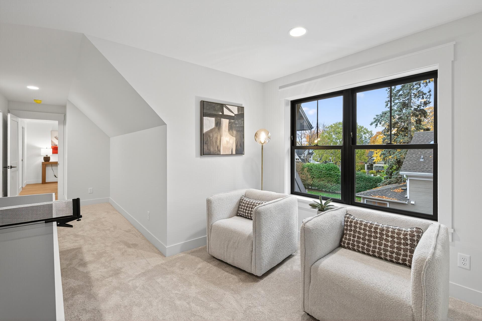 Furnished sitting area with two armchairs beside a large window and a sloped ceiling.