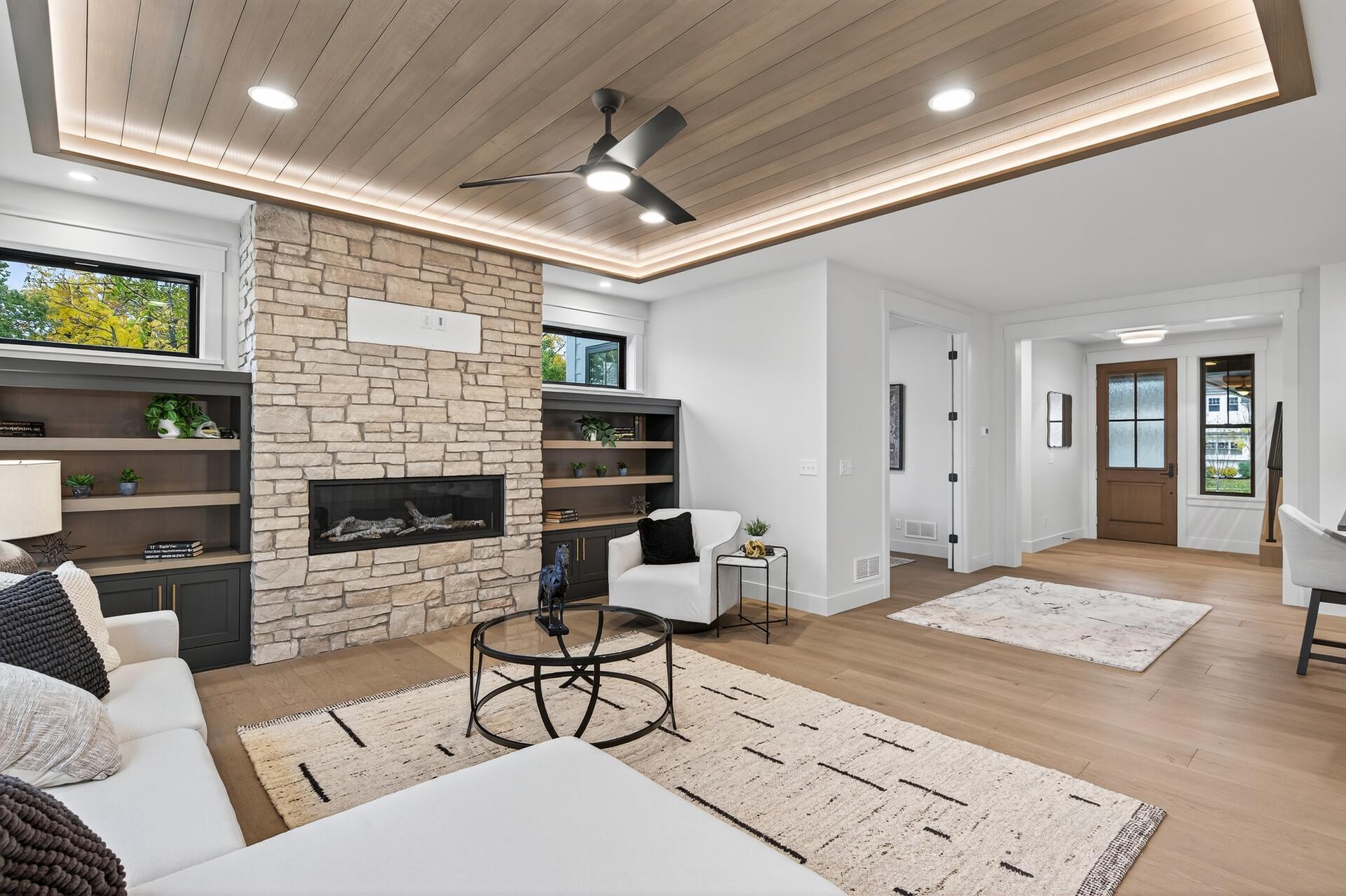 Living room with a stone fireplace, built-in shelves, and a wood-plank ceiling.
