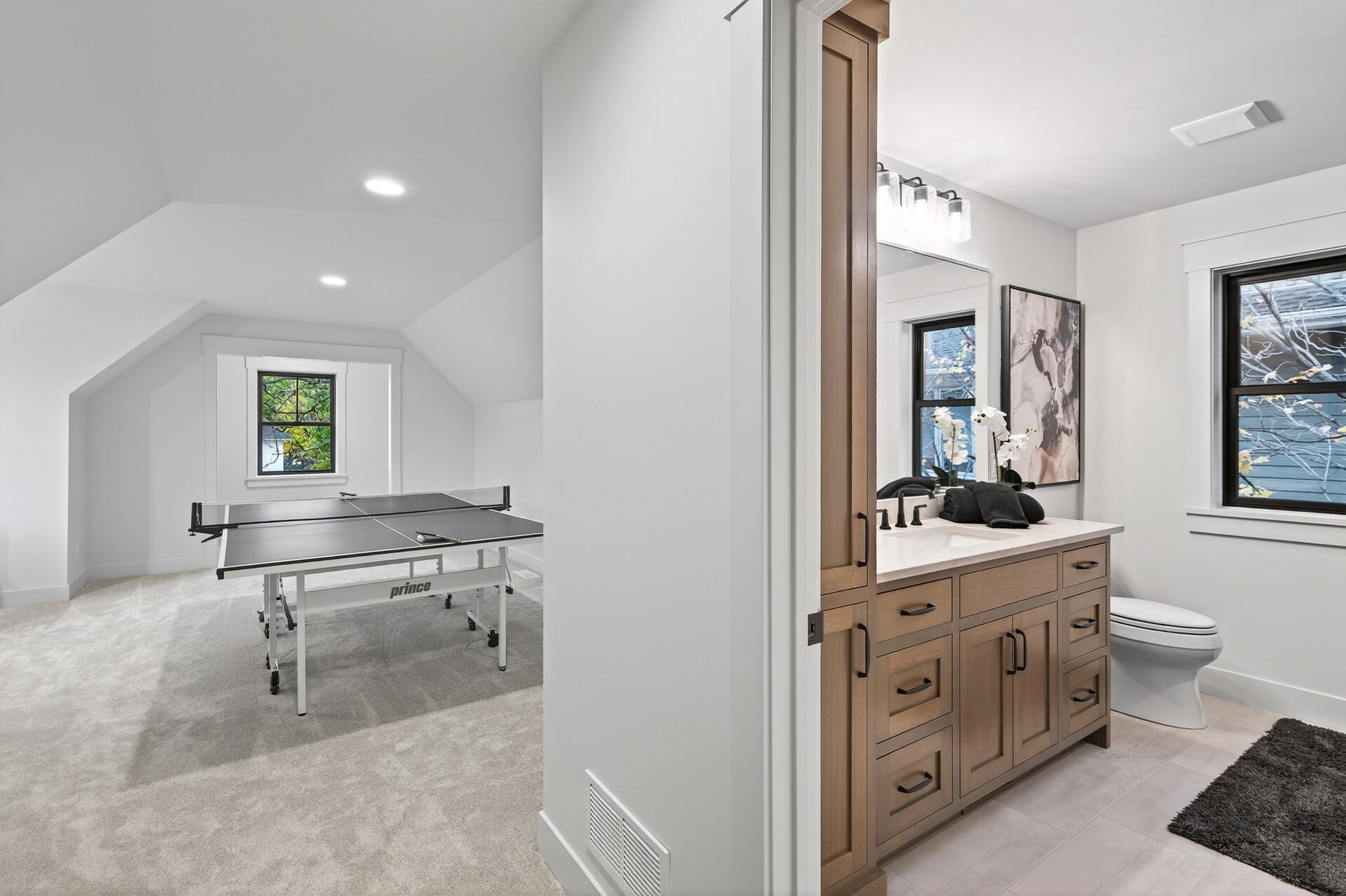 Bathroom vanity beside a carpeted recreation room with a table-tennis table.