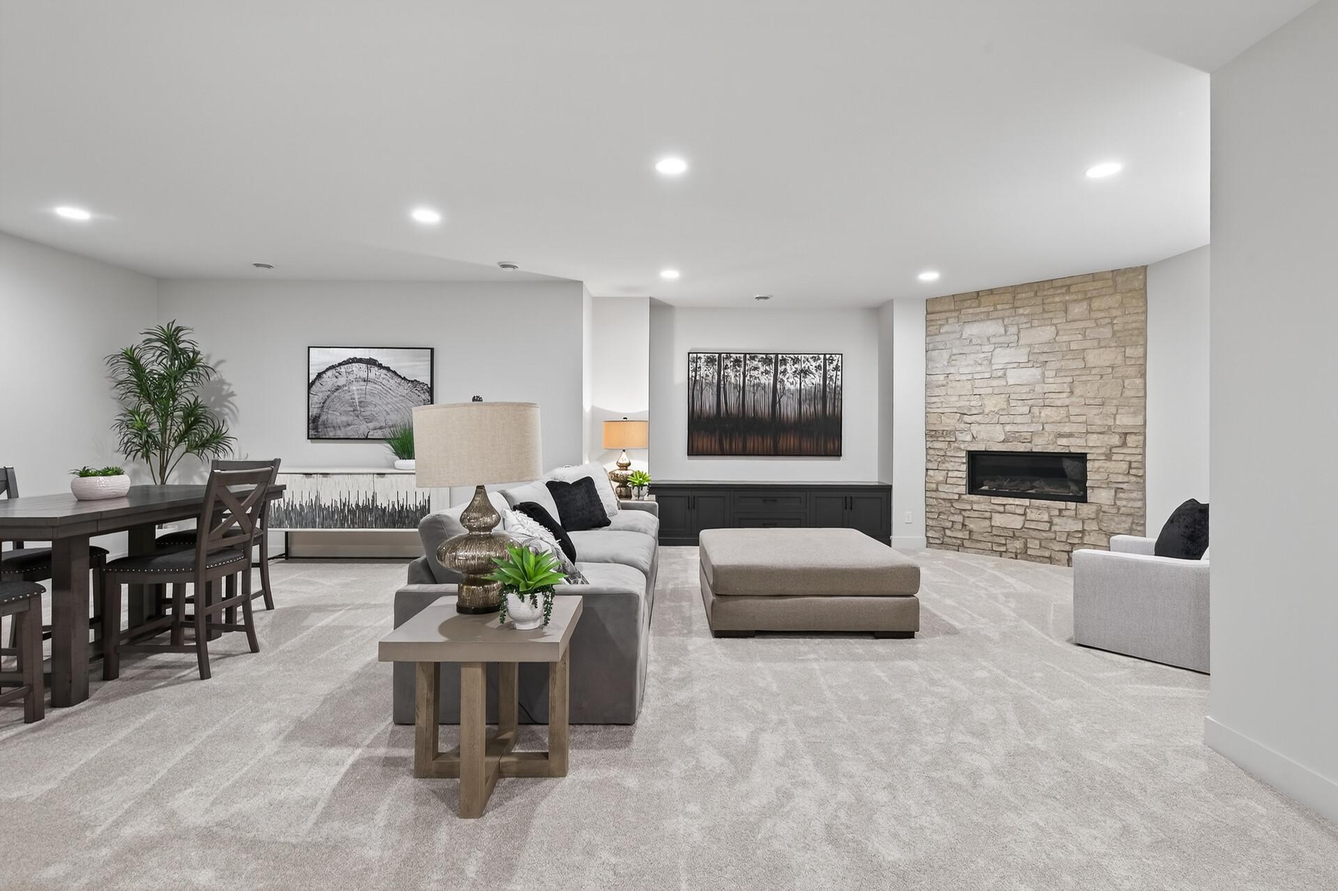 Open-plan living and dining room with a stone fireplace wall and built-in cabinetry.