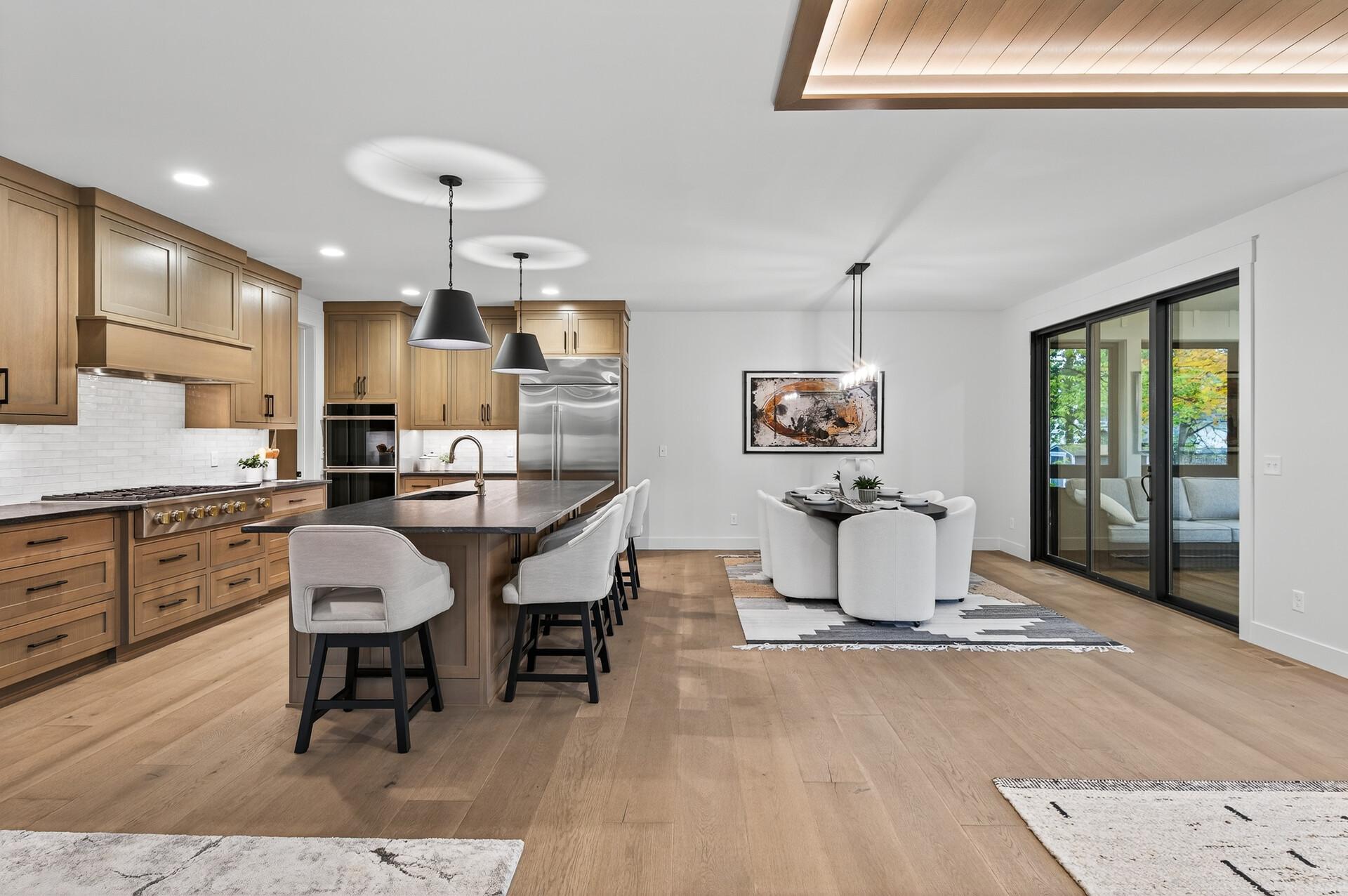 Open-plan kitchen and dining area with a wood-cabinet island and black-framed sliding doors.