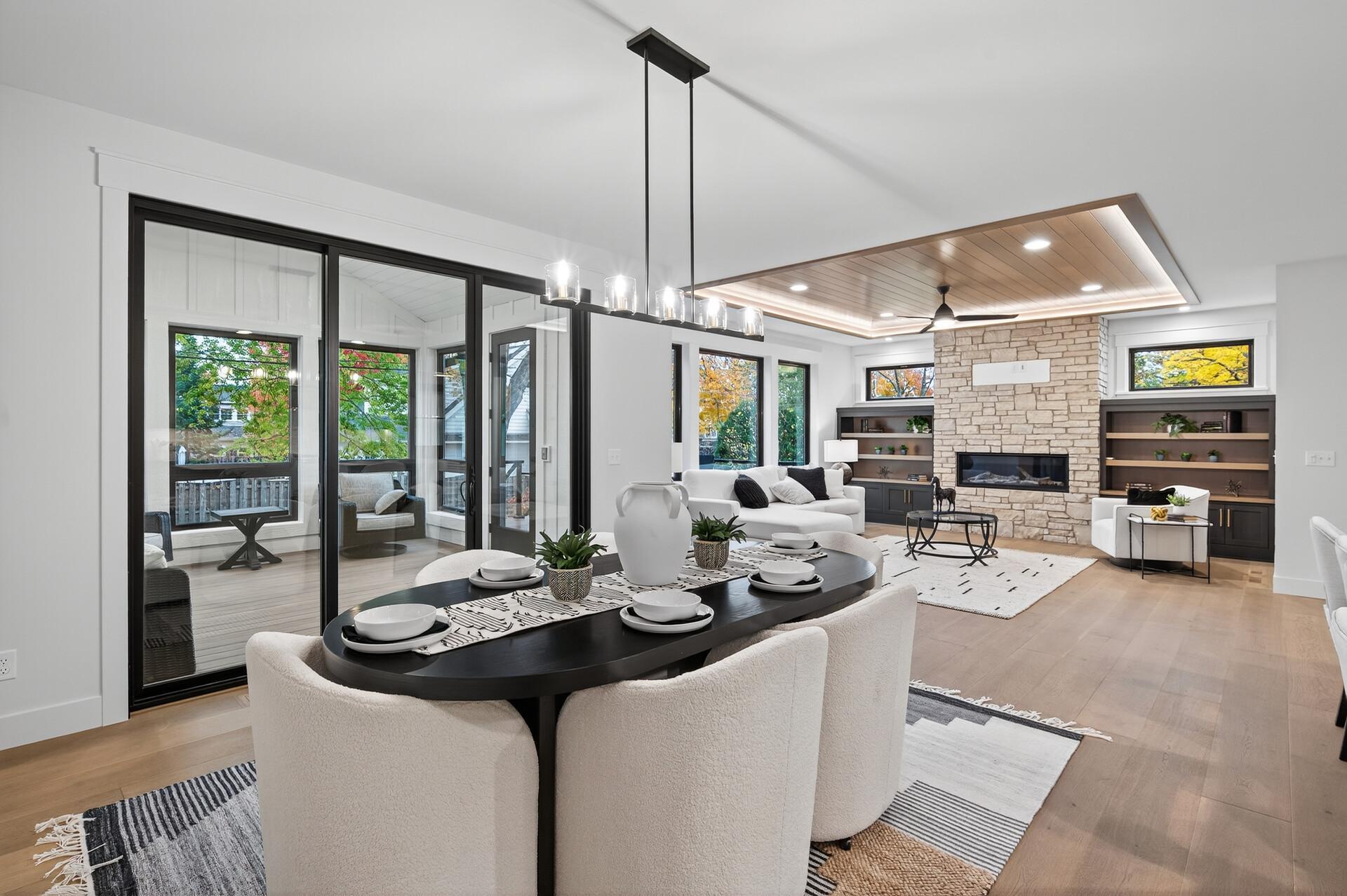 Open-plan living and dining room with a stone fireplace, built-in shelves, and large sliding glass doors.