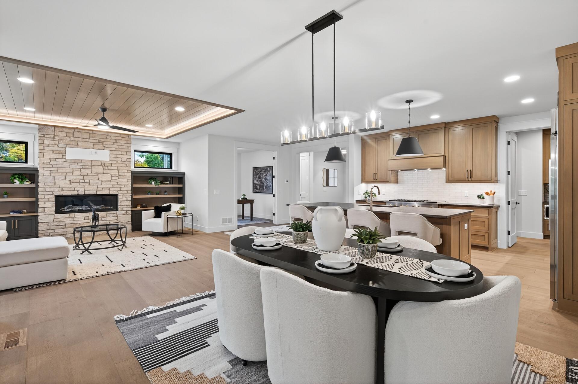 Open-plan kitchen and living room with wood cabinetry, a dark island, and stone fireplace.
