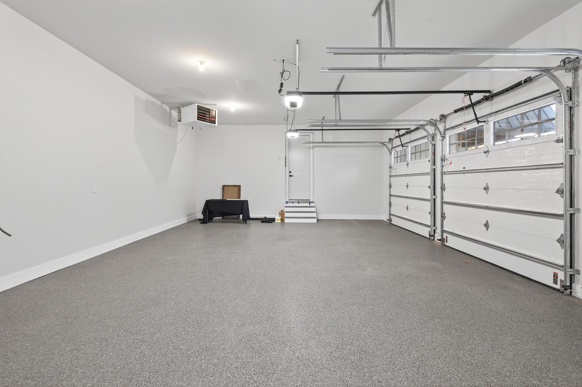 Spacious carpeted two-car garage with two overhead doors and steps to an entry door.