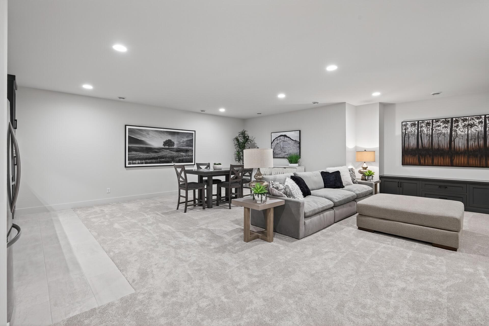 Living and dining area with a gray sectional, ottoman, and dark dining table.