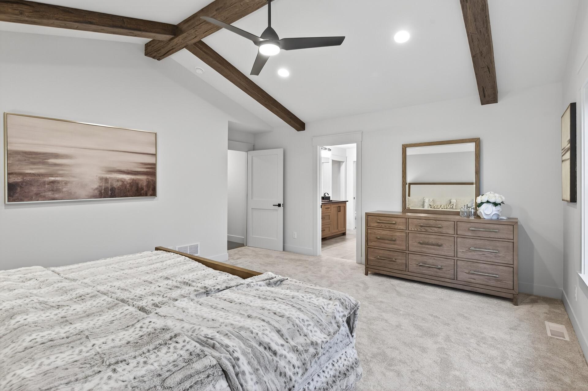 Bedroom with exposed wood ceiling beams, a ceiling fan, and a wood dresser.