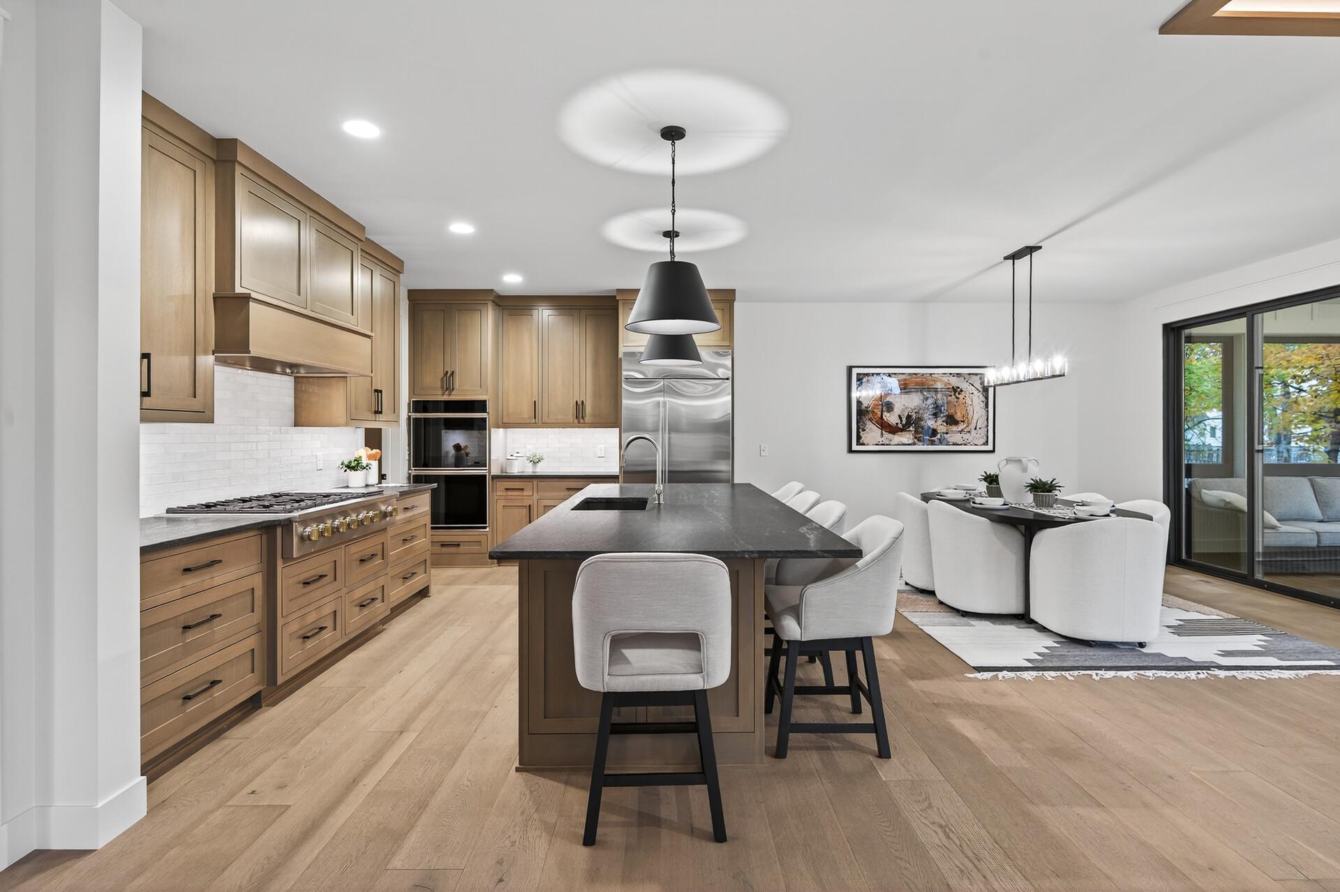 Open kitchen with oak cabinets, a large dark island, and an adjacent dining area.