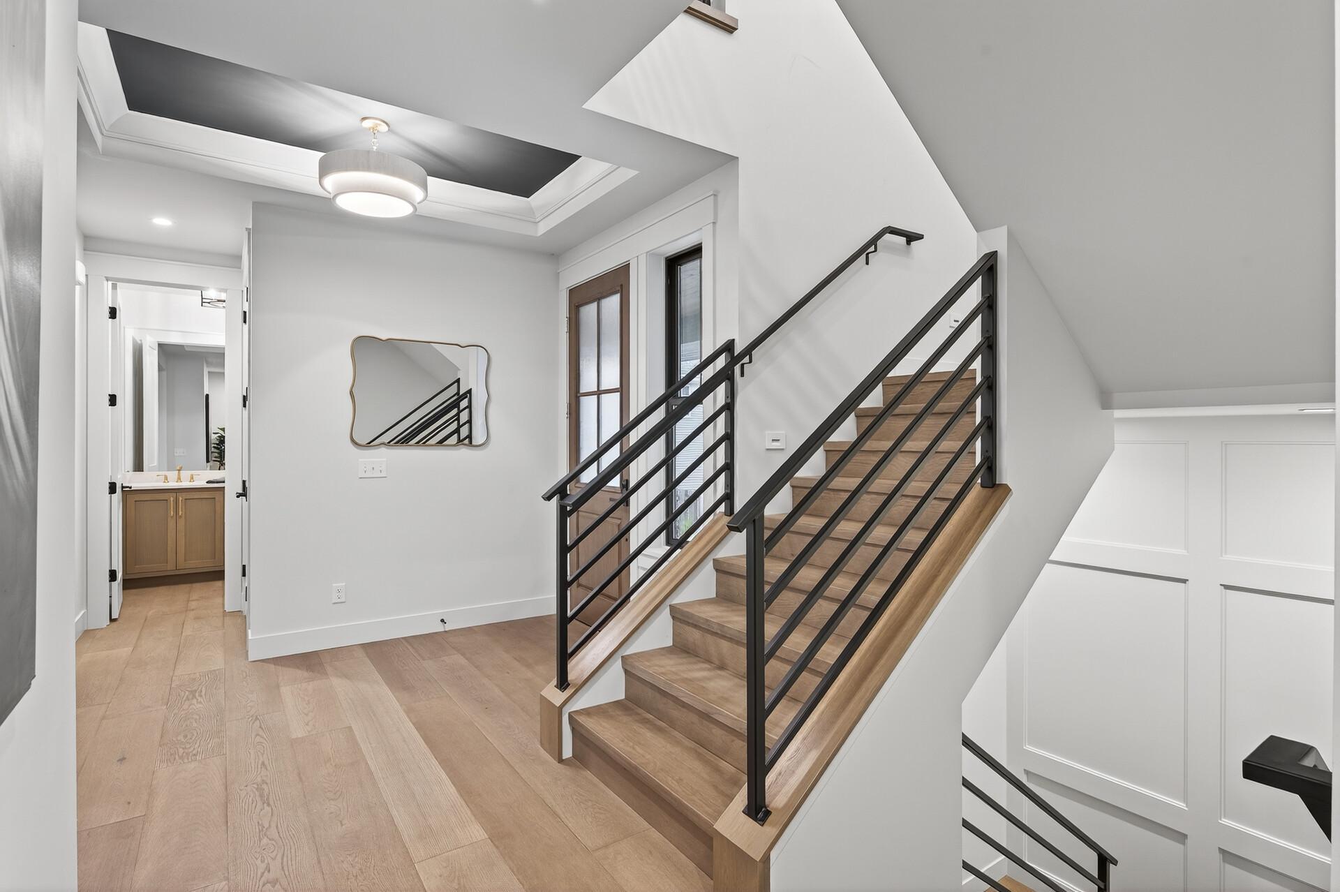 Wood staircase with black metal railings beside a landing and open bathroom doorway.