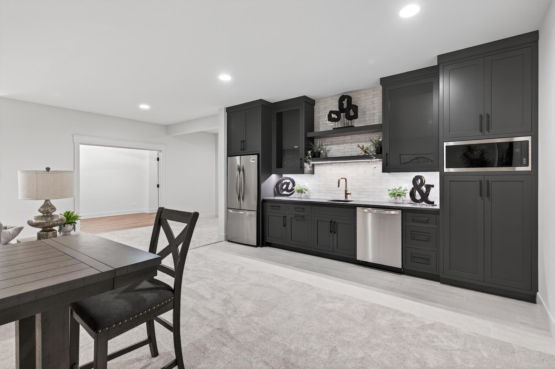 Kitchen with charcoal cabinets, stainless steel appliances, and a white tile backsplash.