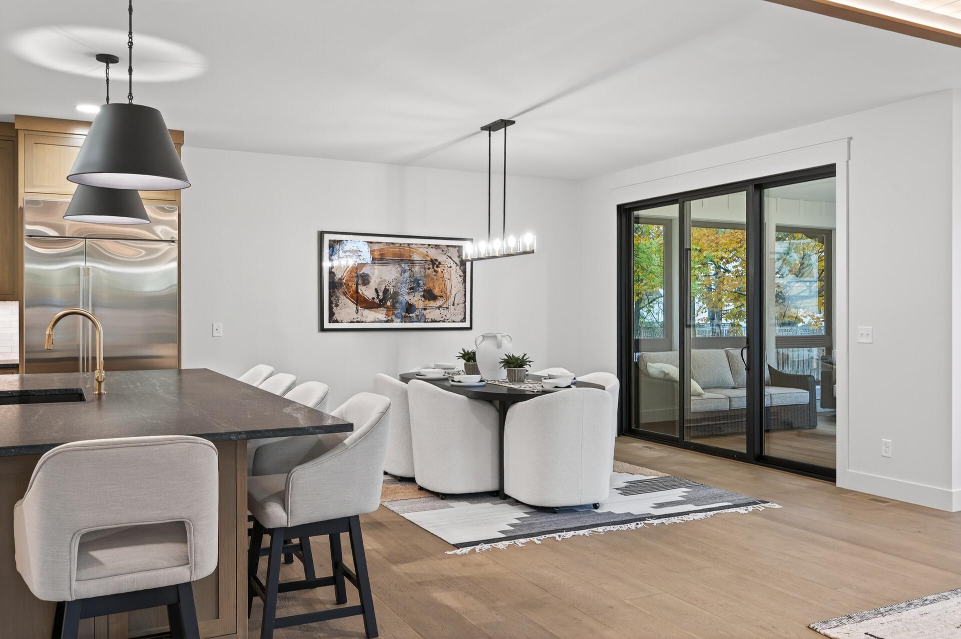 Open-plan kitchen and dining area with a stone island and sliding glass doors to a furnished patio.