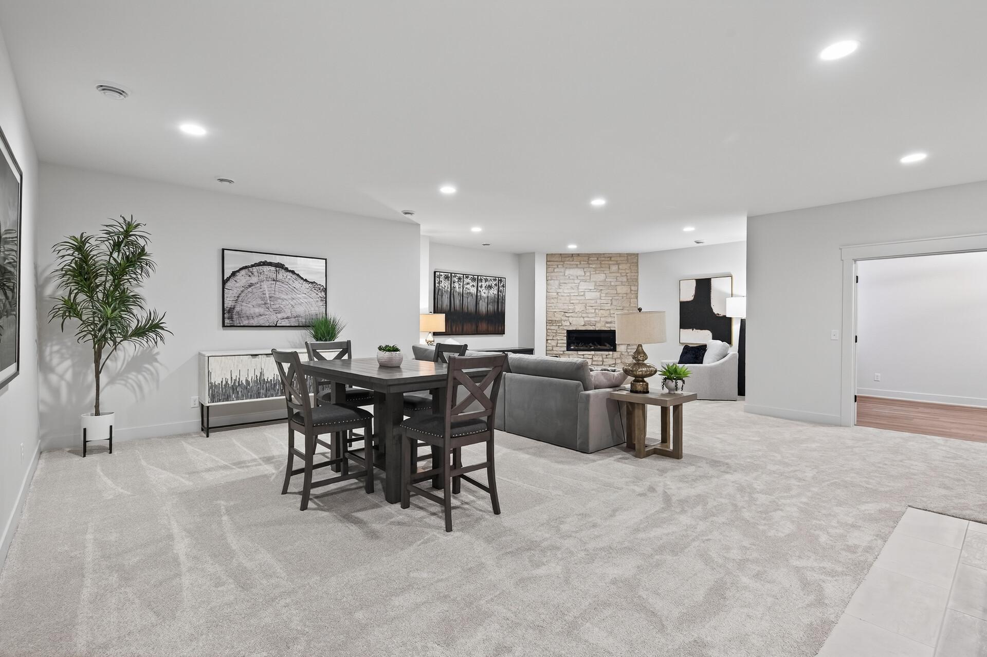 Open-plan living and dining room with a stone fireplace and dark wood dining set.