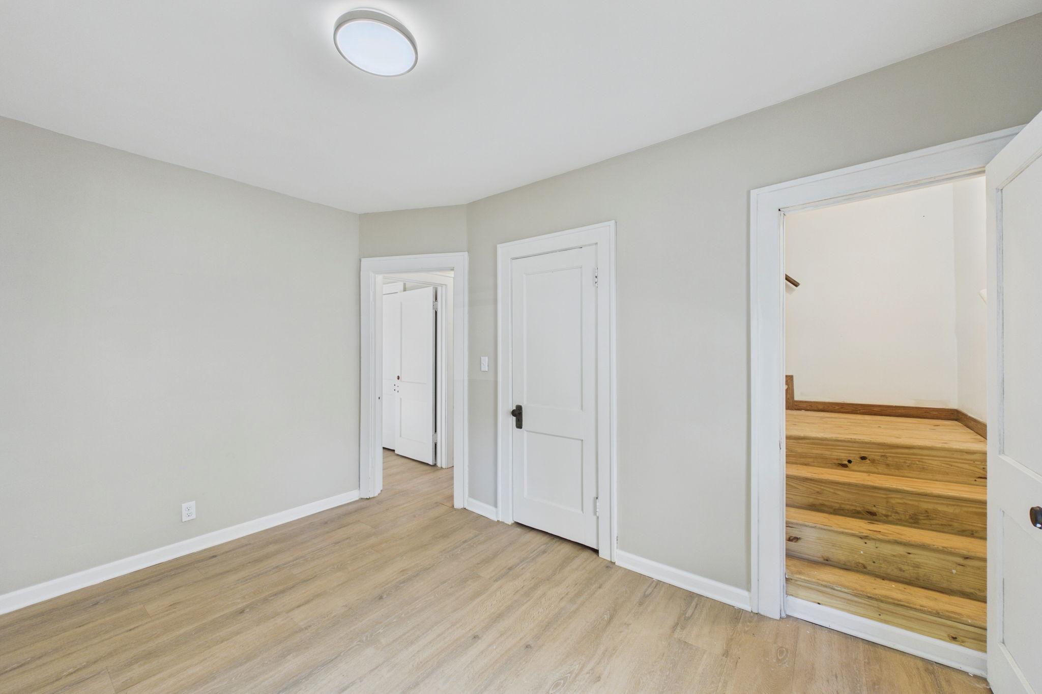Empty room with light wood-look flooring and a doorway opening onto wooden steps.