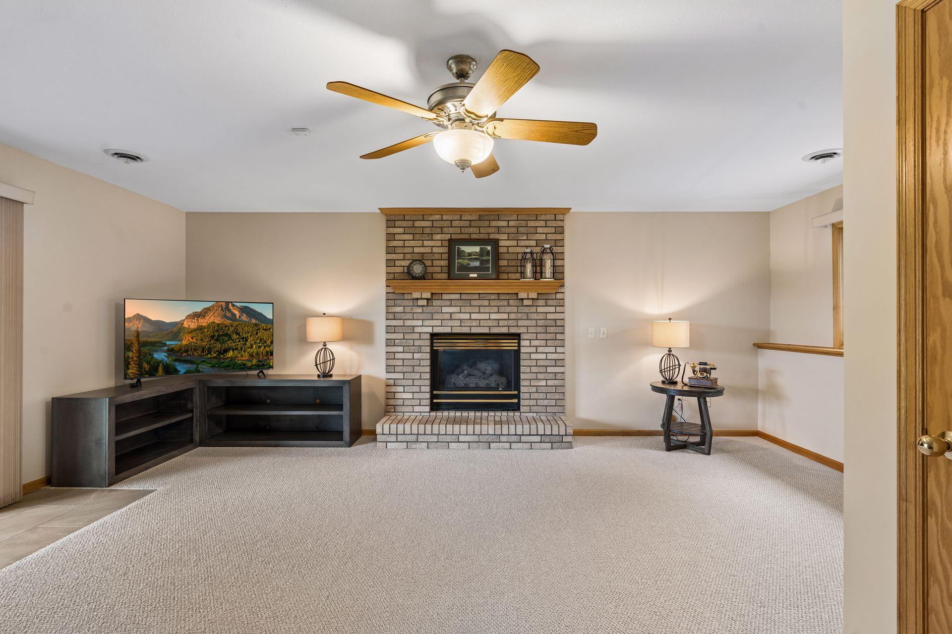 Living room with a brick fireplace, raised hearth, and ceiling fan.