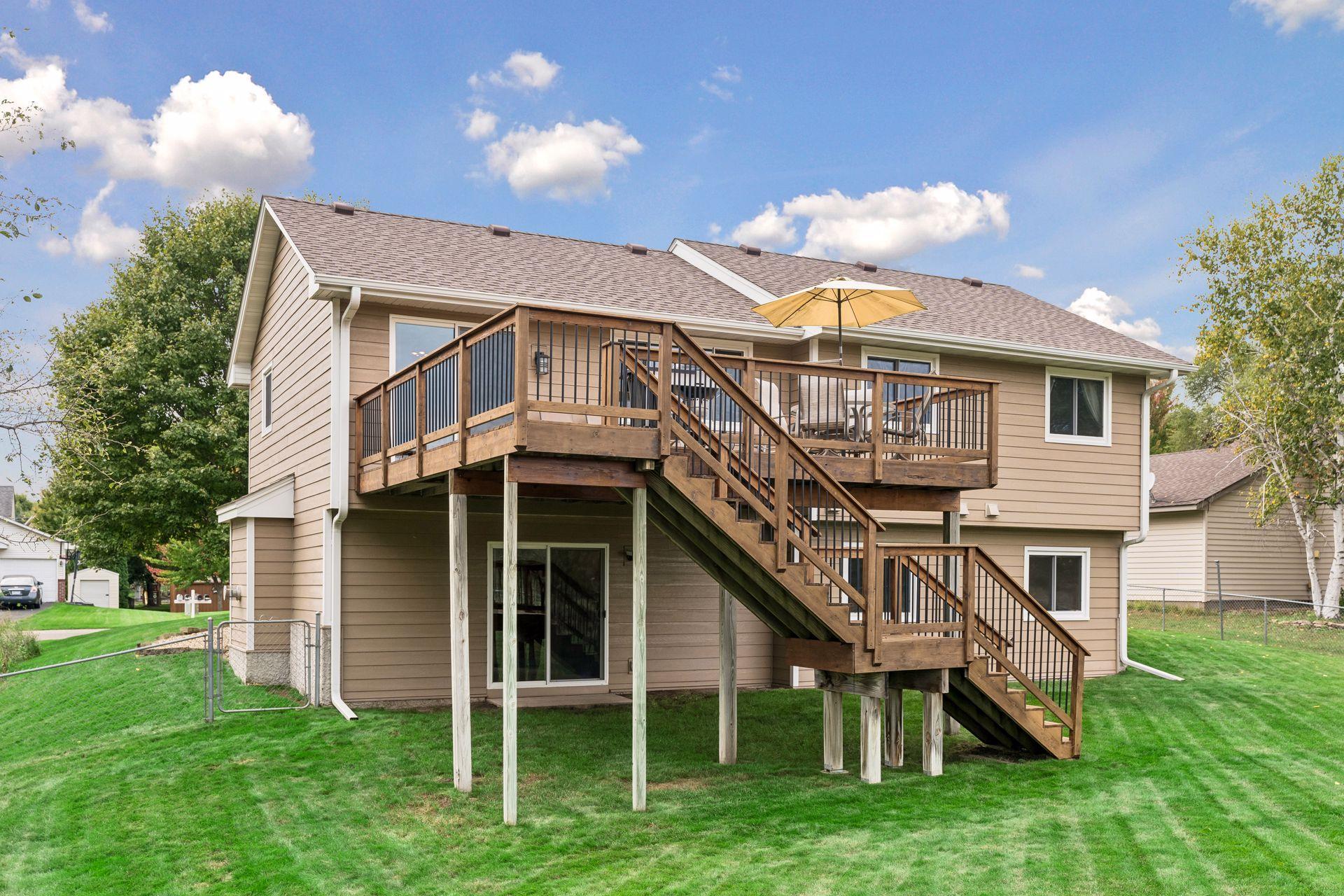 Tan home with elevated wood deck, exterior stairs, and a yellow patio umbrella.