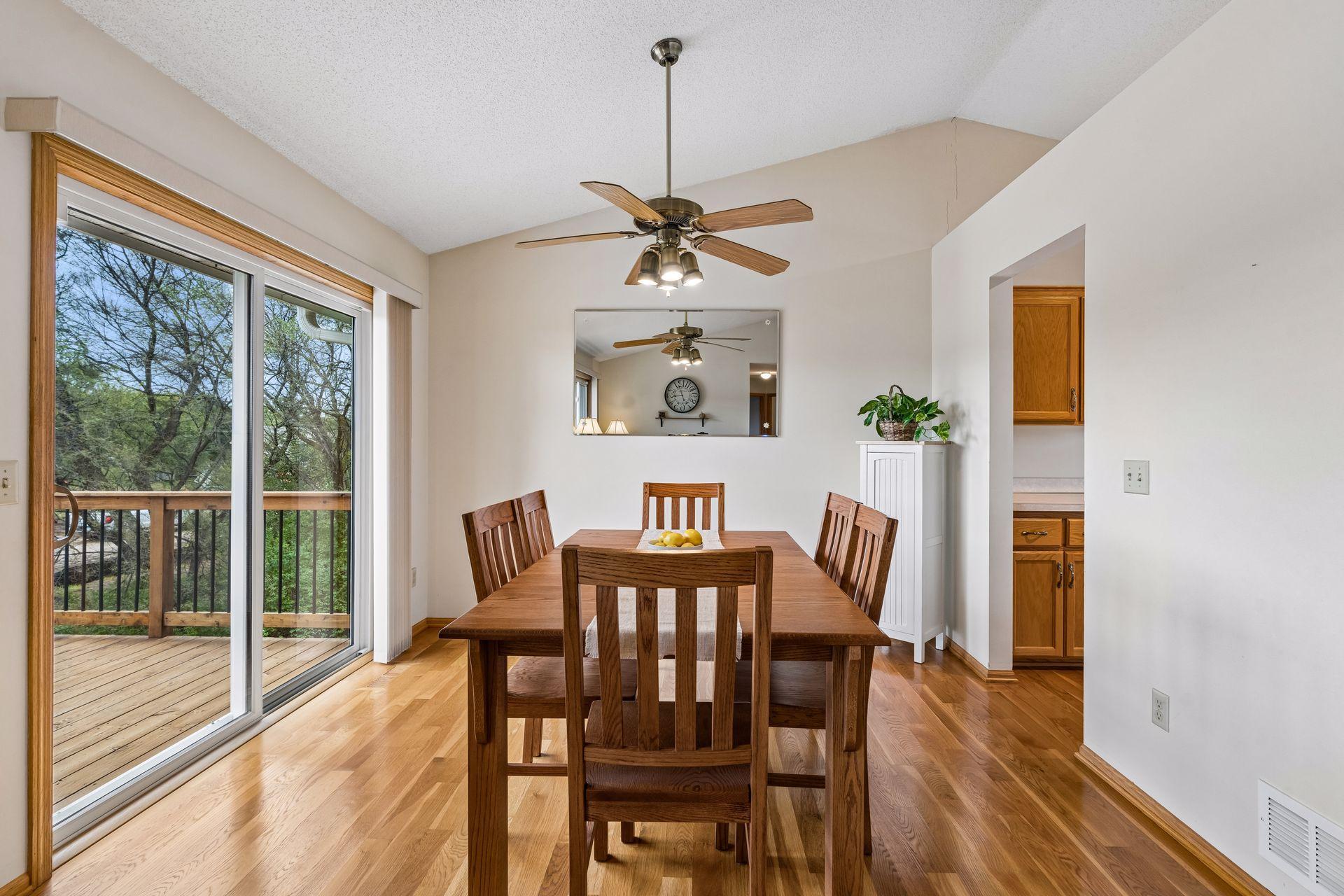 Dining room with a dark wood table, hardwood floors, and sliding doors to a tree-lined deck.