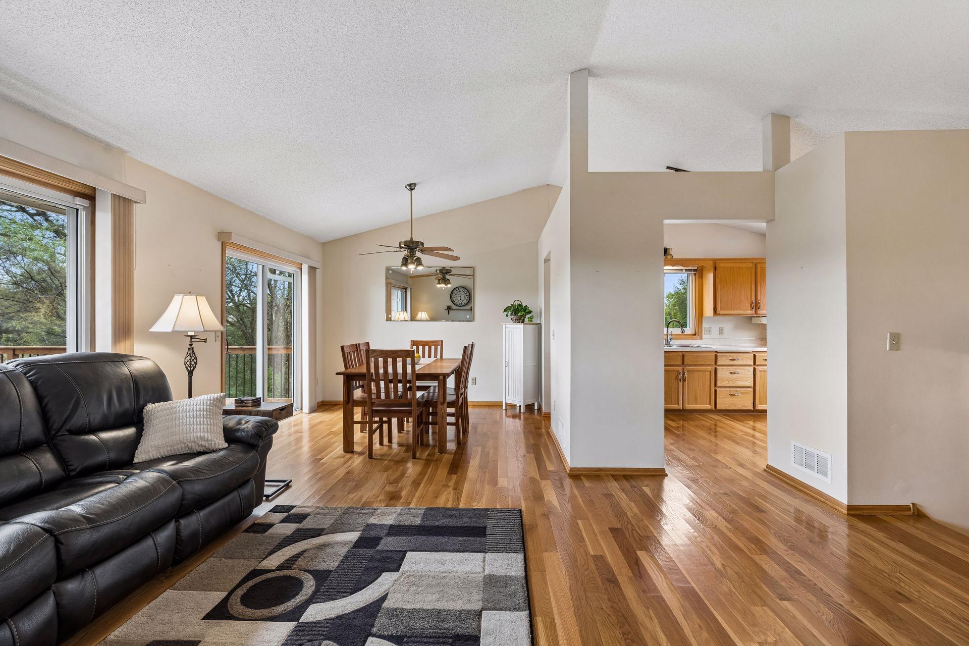 Open living and dining area with hardwood floors, a leather sofa, and sliding doors to a deck.