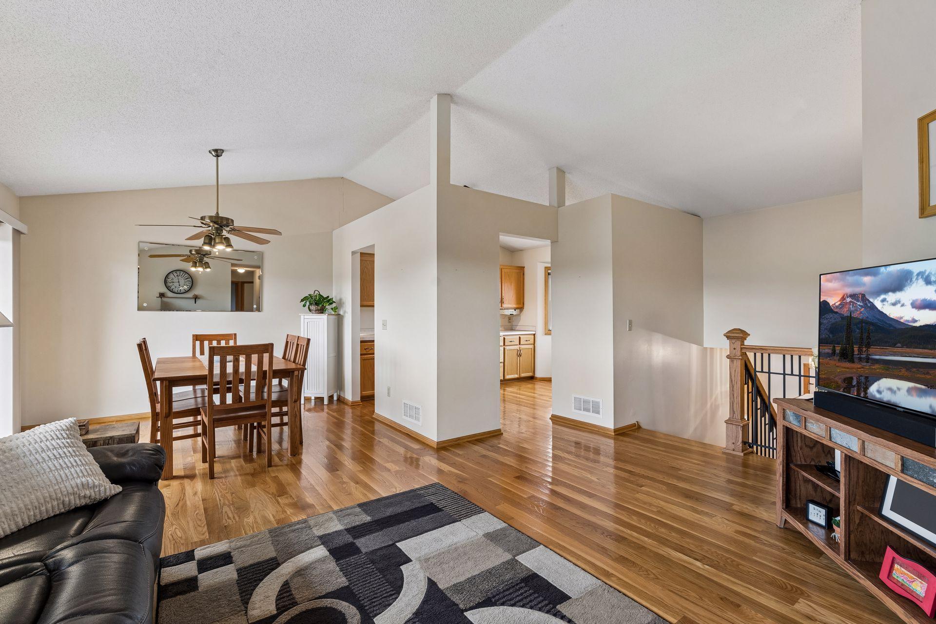 Open living and dining area with hardwood floors, dining set, and staircase railing.