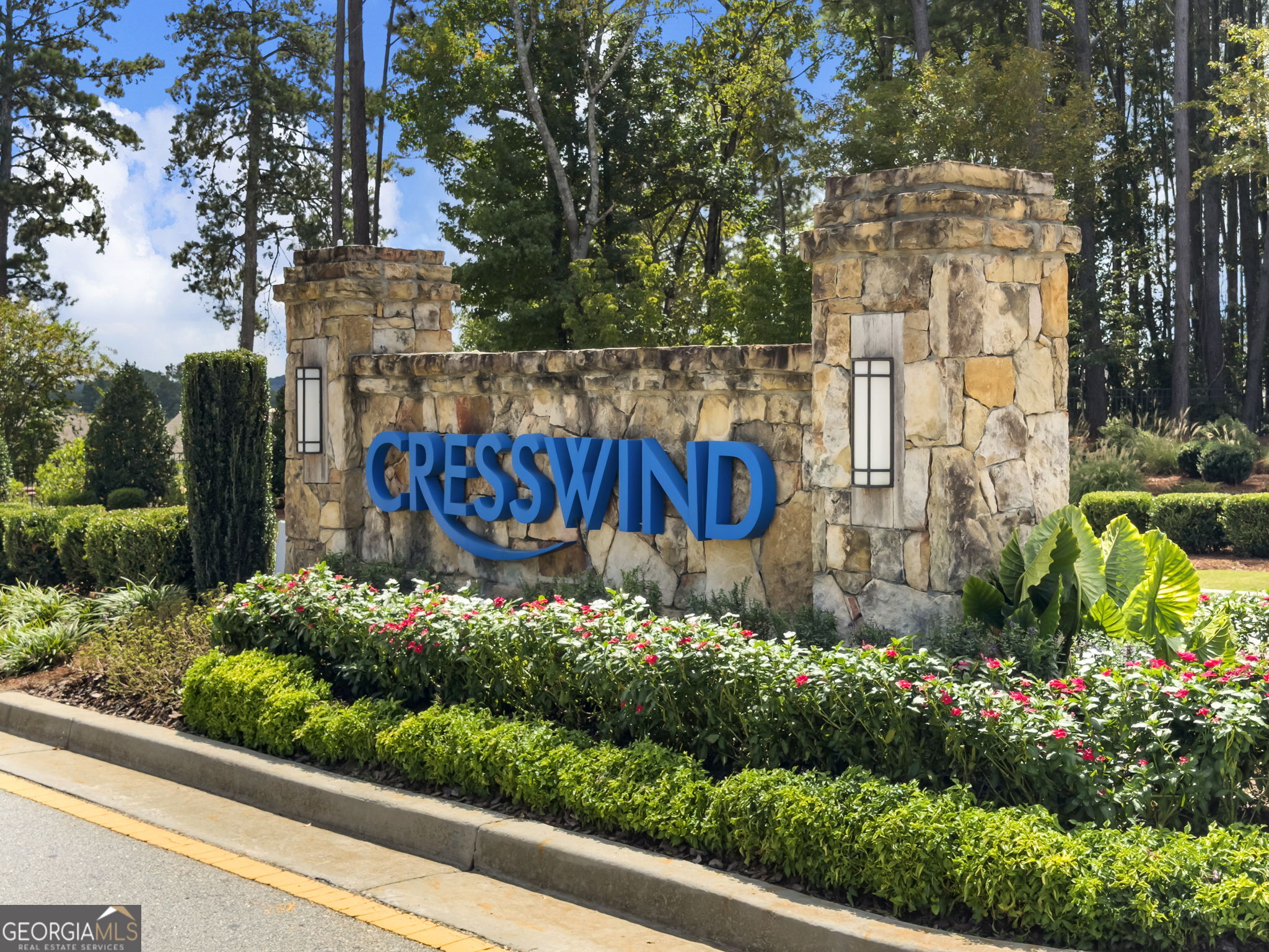 Cresswind community entrance sign set in stone, surrounded by flowering shrubs and mature trees.