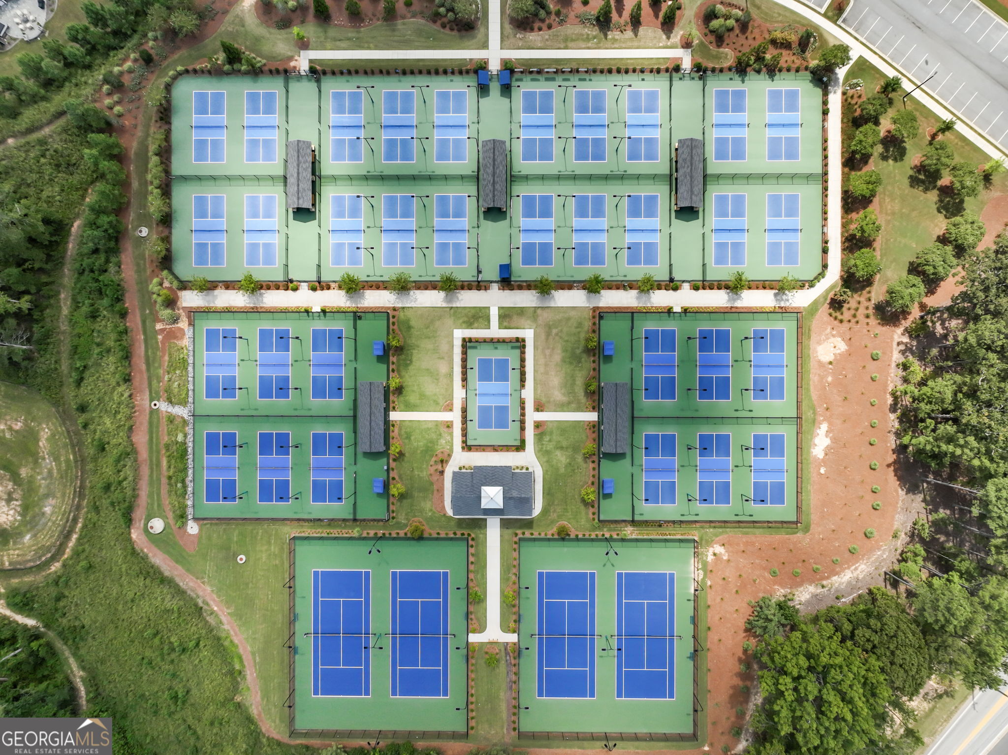 Aerial view of numerous blue courts arranged across a landscaped sports complex.