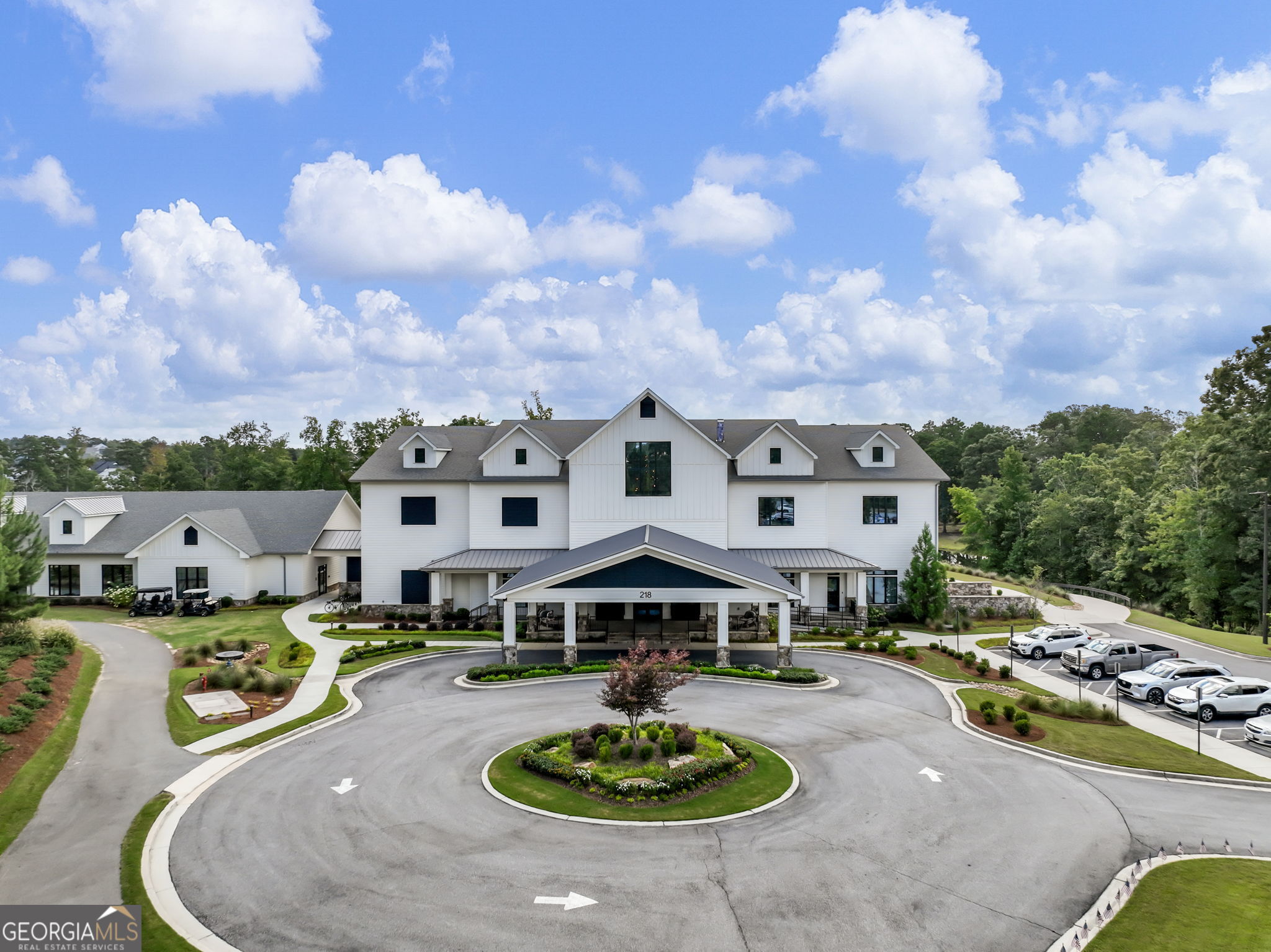 Large white multi-gabled building with a covered entrance and landscaped circular driveway.