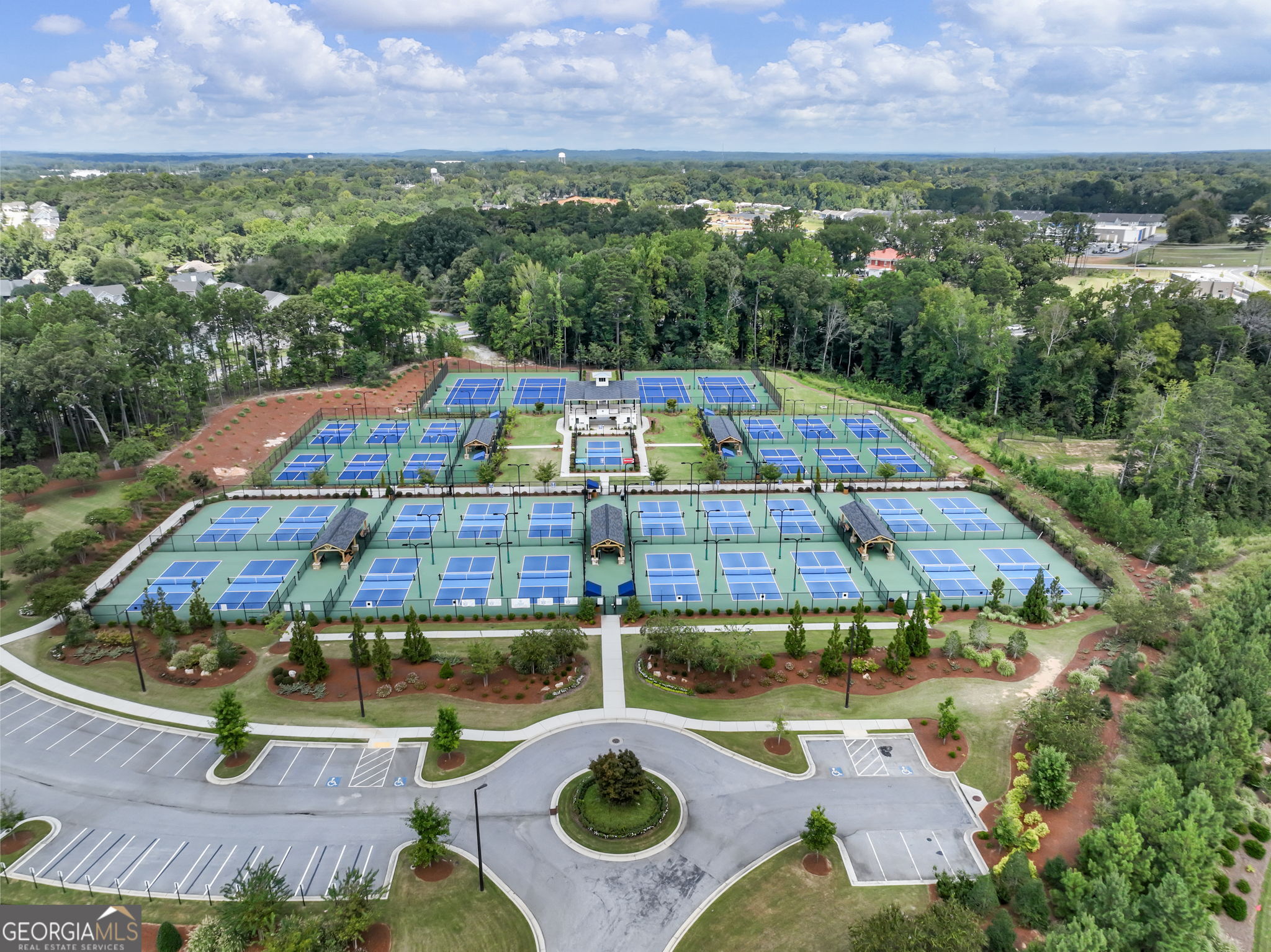 Aerial view of a tennis facility with rows of blue courts and a central clubhouse.