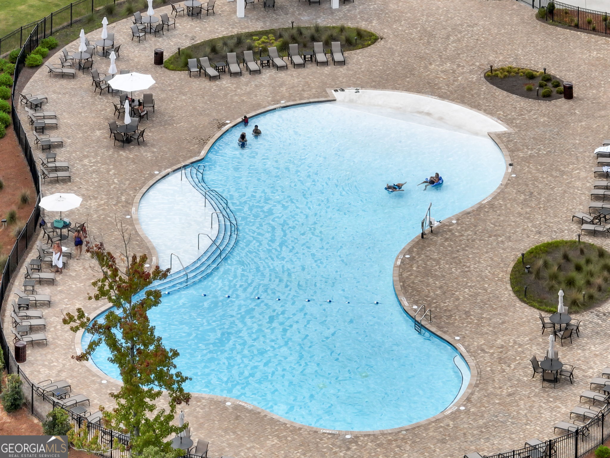 Outdoor swimming pool with a curved shape, brick-paved deck, and surrounding lounge chairs.