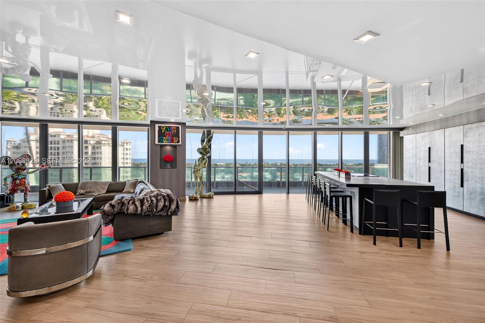 Furnished high-rise living and dining area with ocean views and floor-to-ceiling windows.