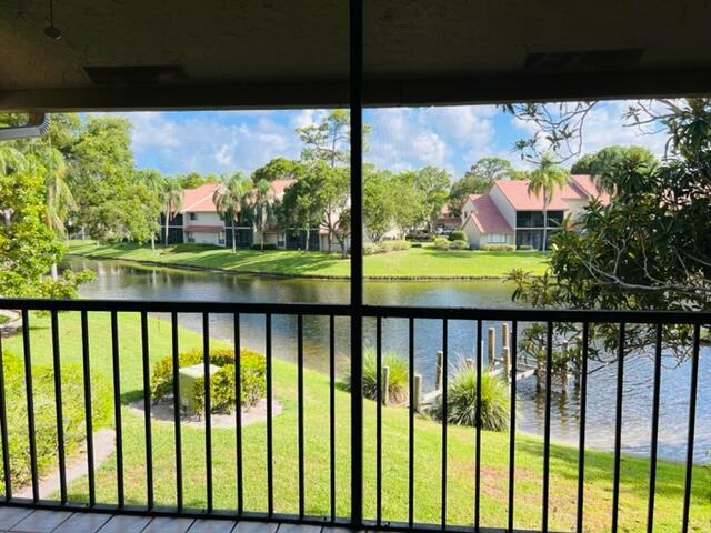 Canal view from a covered balcony, with waterfront homes and palms across the water.