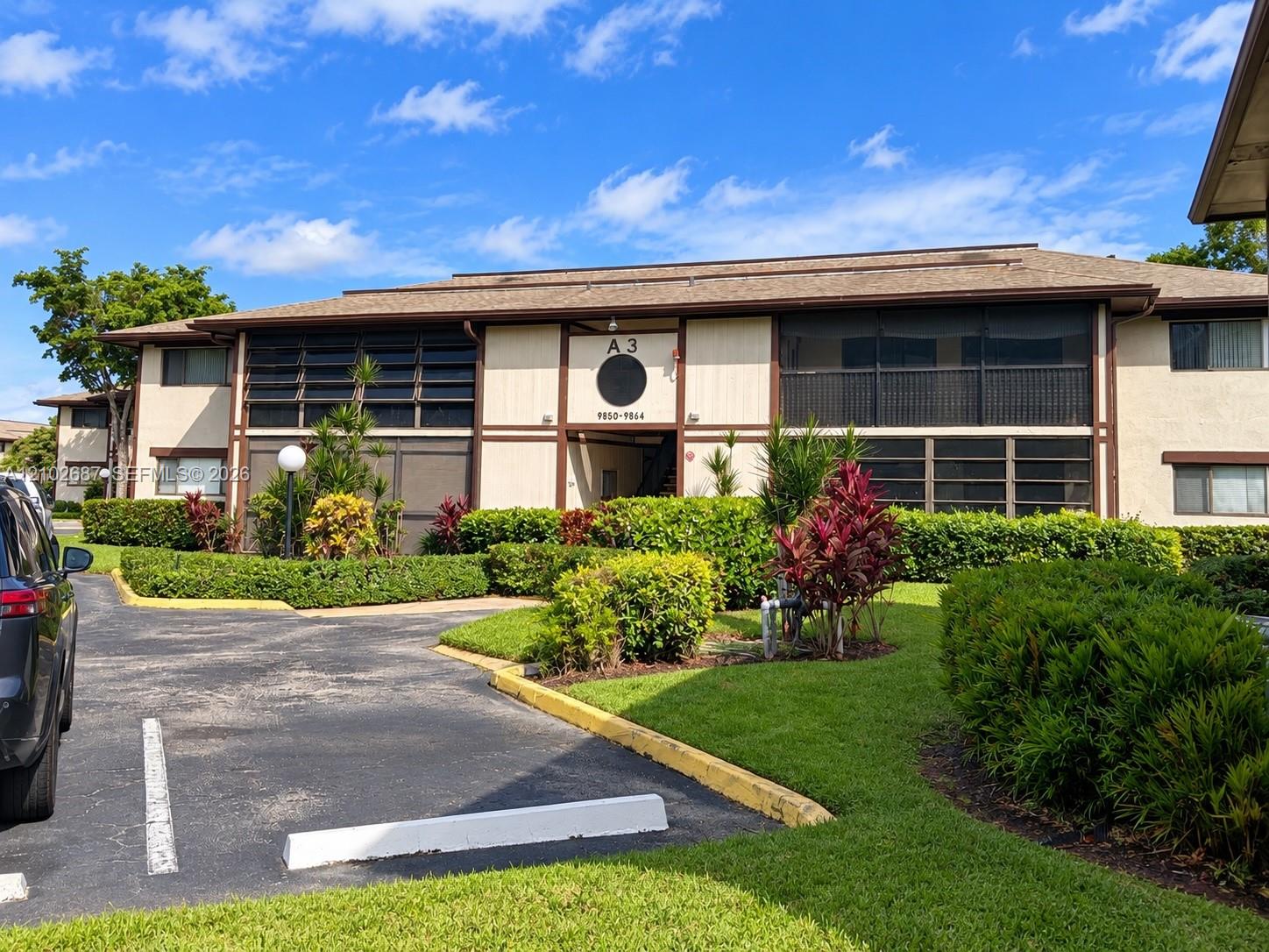 Two-story condominium exterior with screened balconies, tropical landscaping, and a central entrance marked A3.