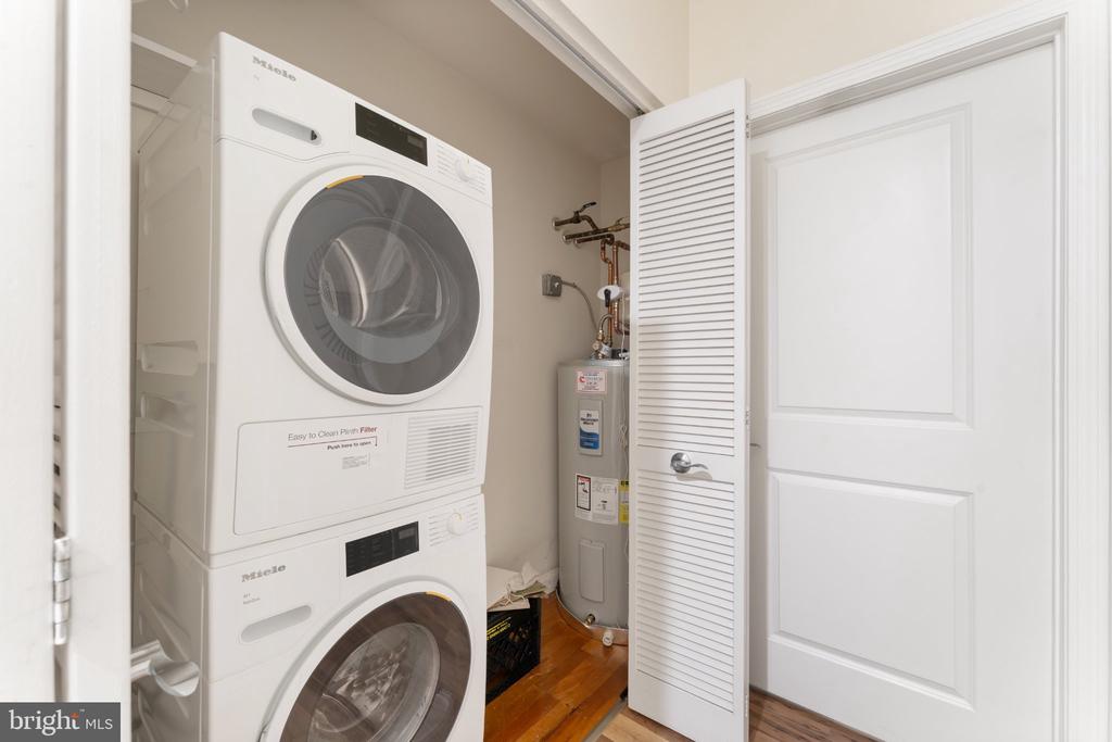 Laundry closet with stacked Miele washer and dryer beside a water heater.