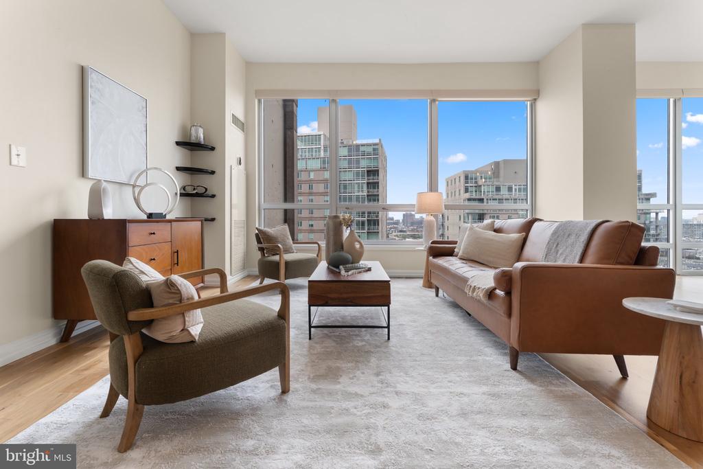 Staged high-rise living room with a leather sofa and floor-to-ceiling windows overlooking the city.