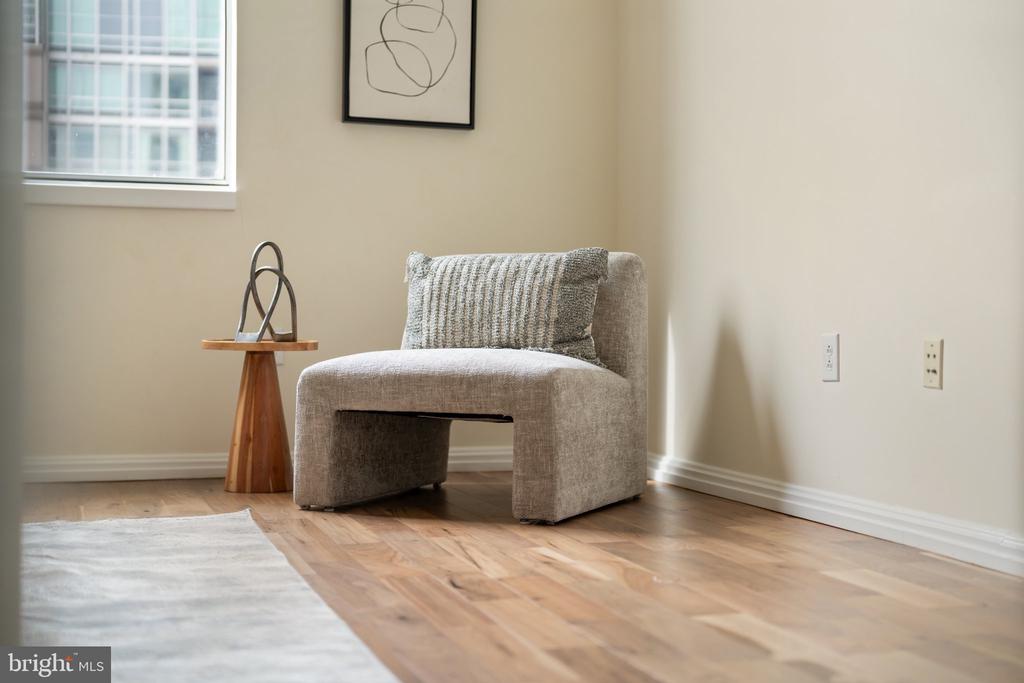 Gray upholstered accent chair beside a wooden side table on hardwood flooring.