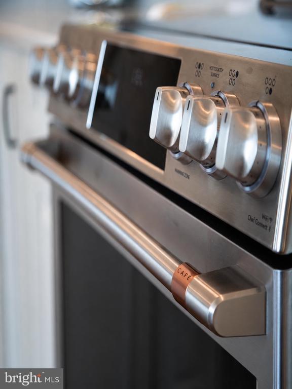 Stainless steel Café range with prominent control knobs and oven handle