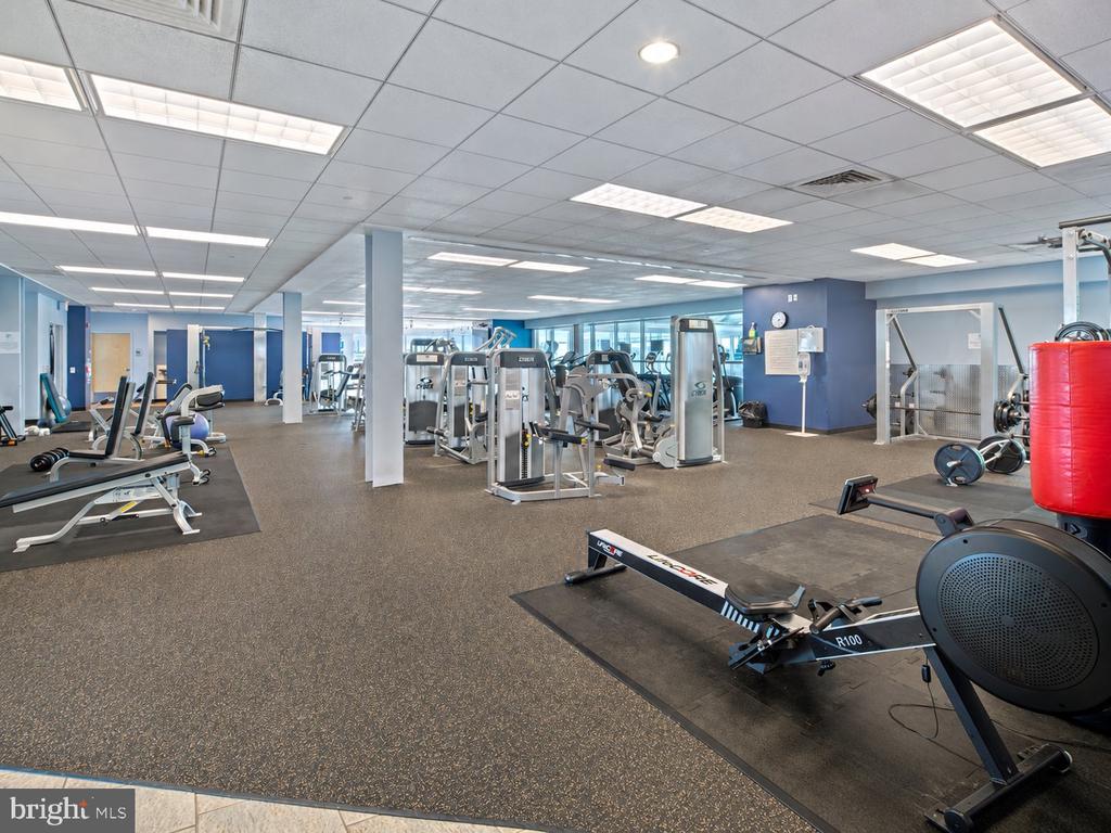 Fitness center with rows of weight machines and a rowing machine in the foreground.