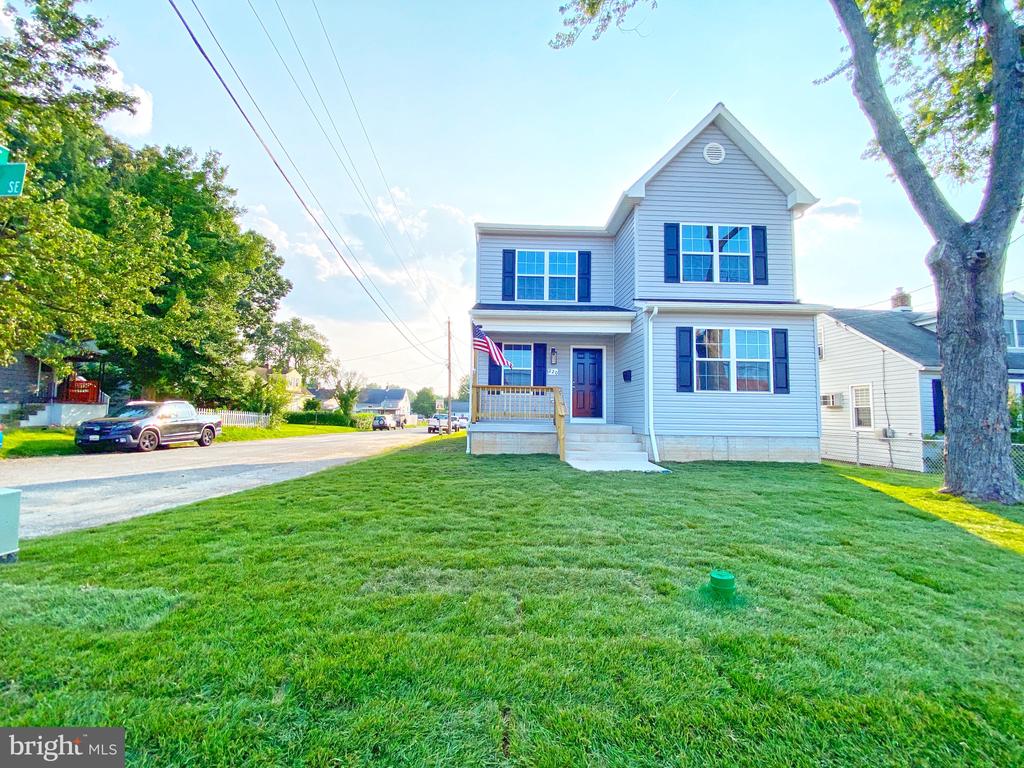 Light-blue two-story house with dark shutters, a front porch, and a broad lawn.
