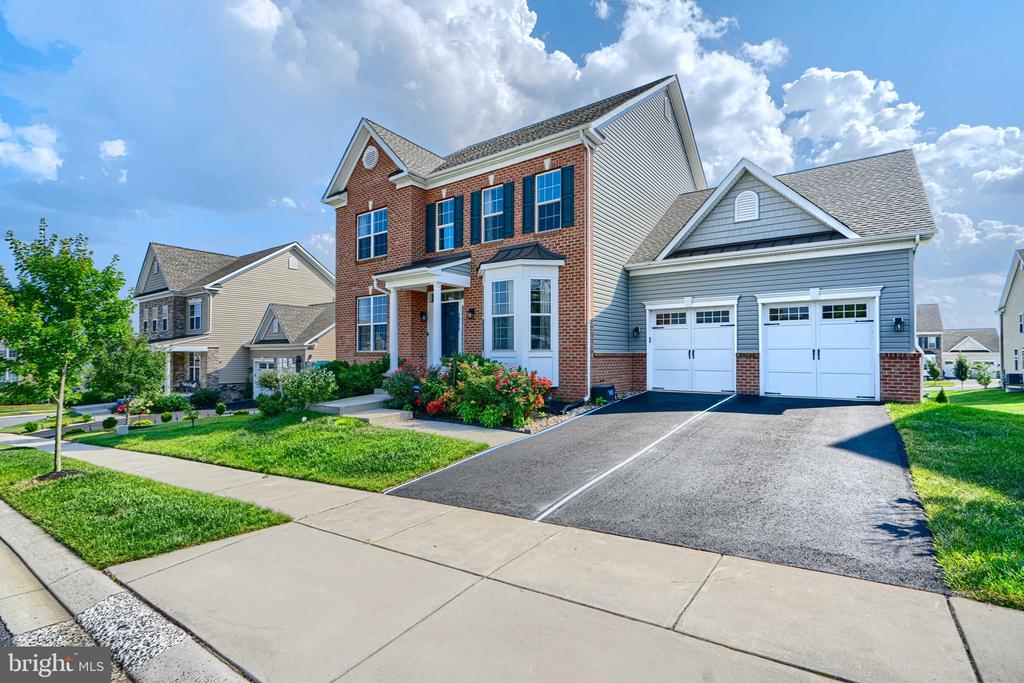 Two-story brick and blue-gray home with an attached two-car garage and landscaped front yard.