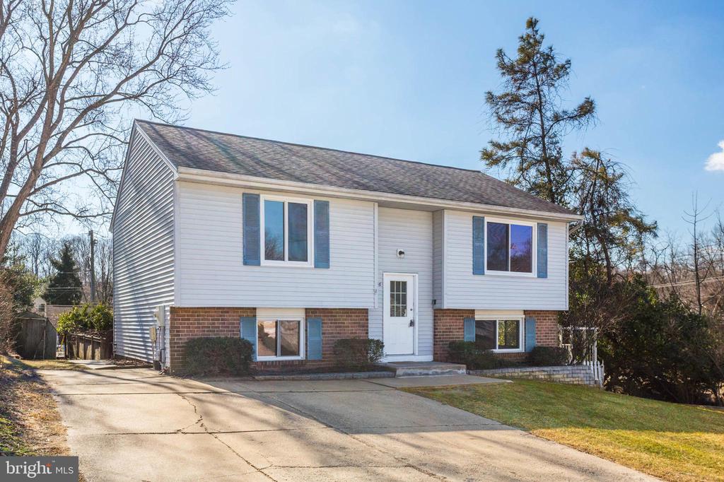 Split-level home with white siding, brick lower facade, blue shutters, and a wide driveway.