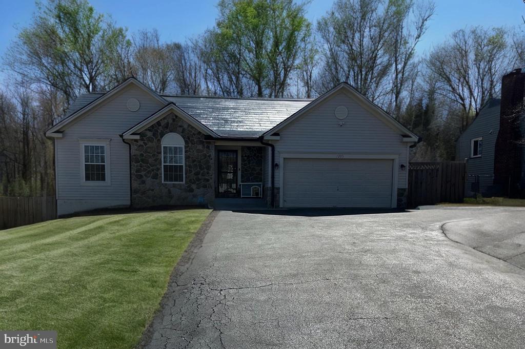 Single-story gray home with a stone facade, attached garage, and broad driveway.