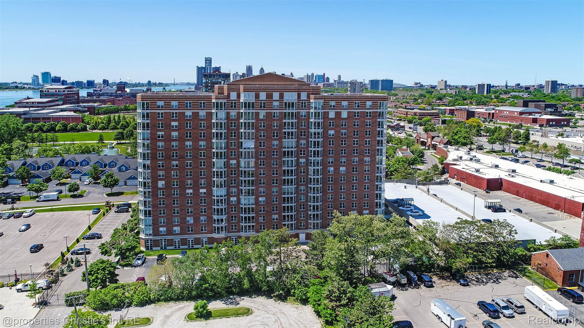 Brick residential building viewed from above, with the Detroit skyline and river in the background.