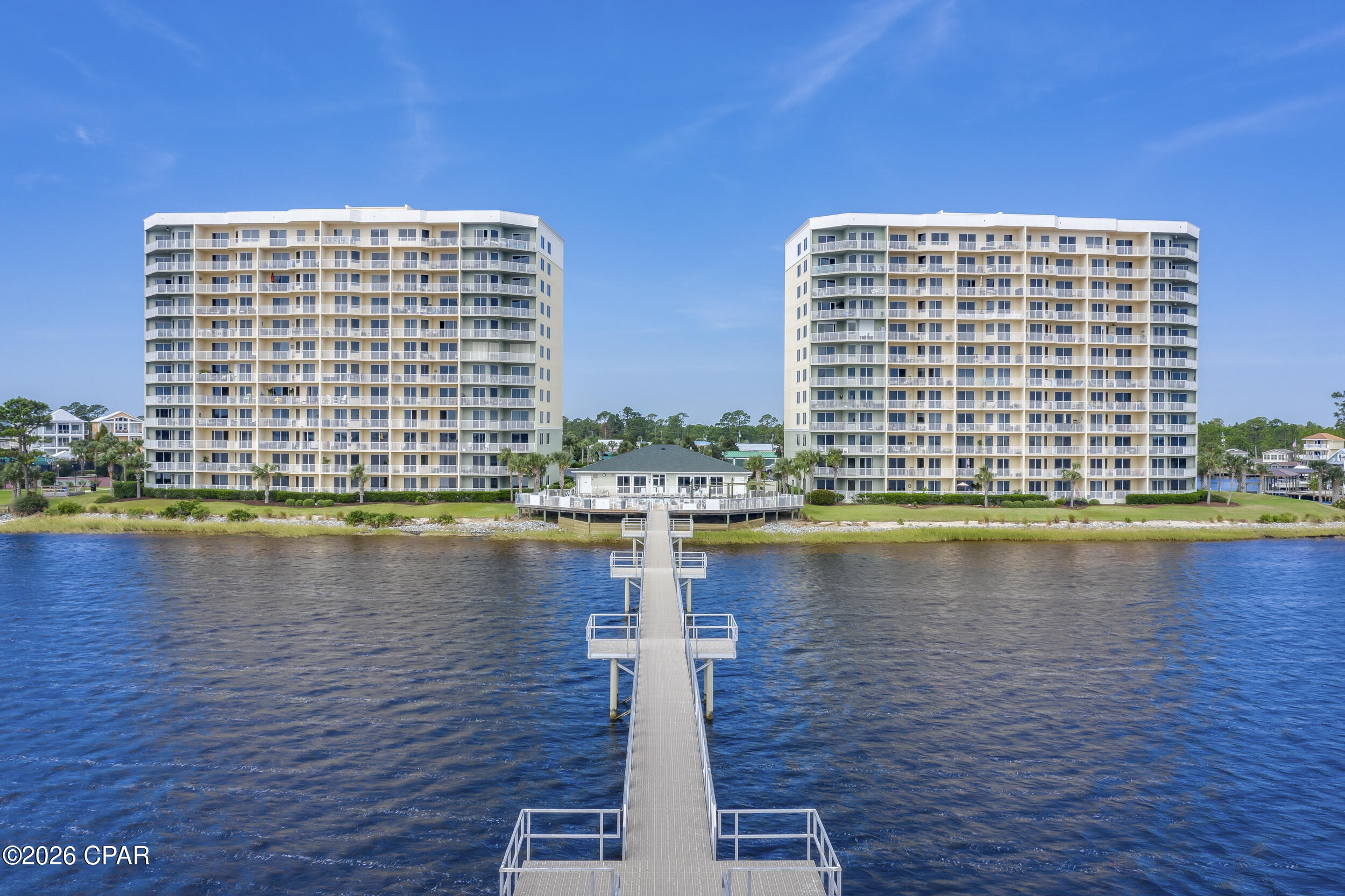 Two waterfront condominium buildings with a long pier extending across the water.