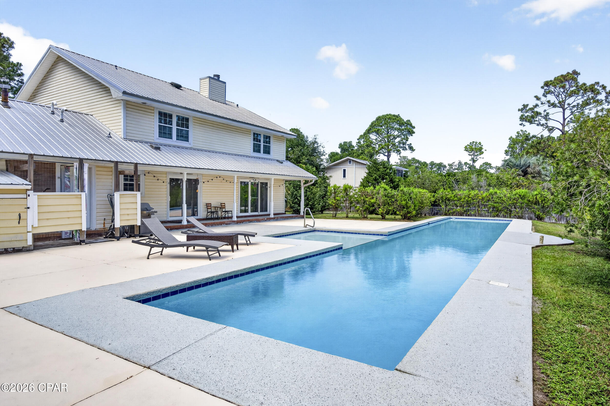 Two-story home with a covered patio beside a large outdoor swimming pool.