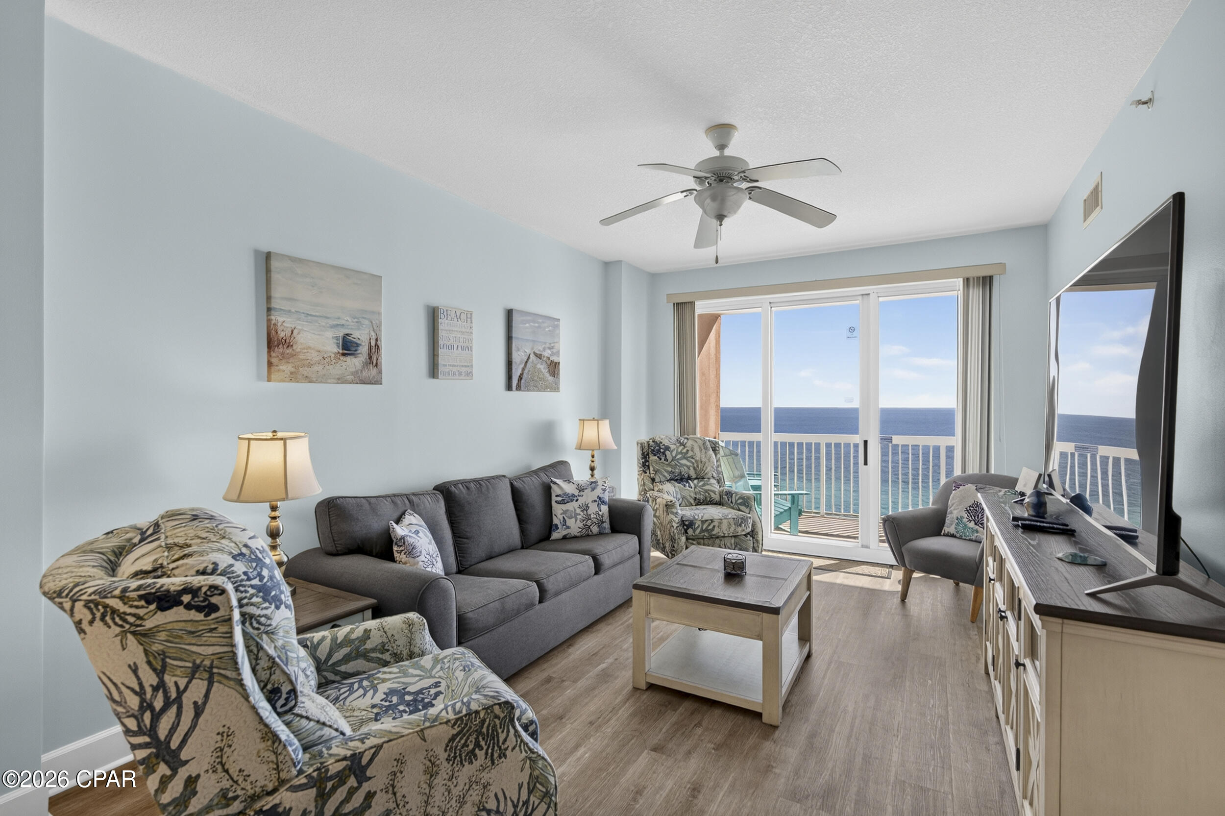 Furnished coastal living room with patterned armchairs and sliding doors overlooking the ocean.