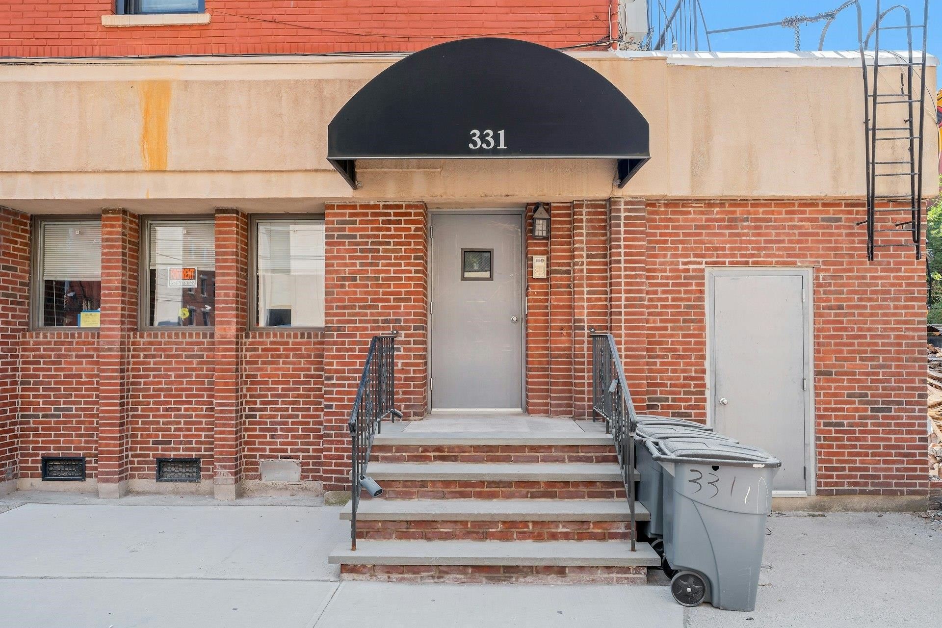 Brick building entrance with steps, a black awning marked 331, and a gray door.