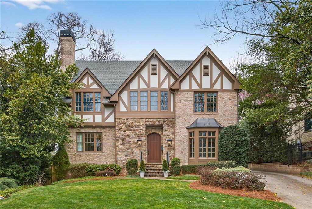 Tudor-style home with stone walls, timbered gables, and a central arched entrance.