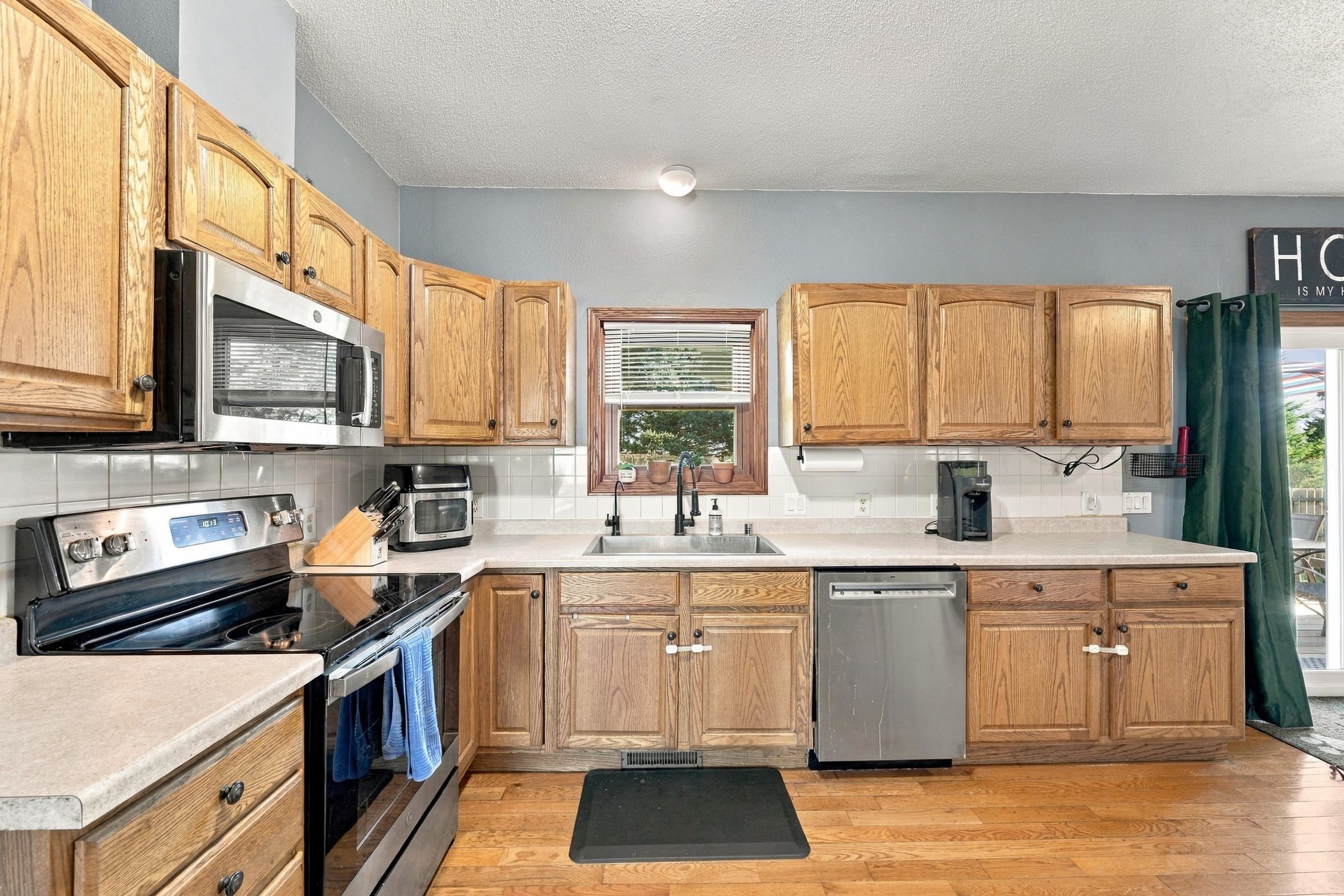 Kitchen with oak cabinets, stainless steel appliances, and a sink beneath a window.